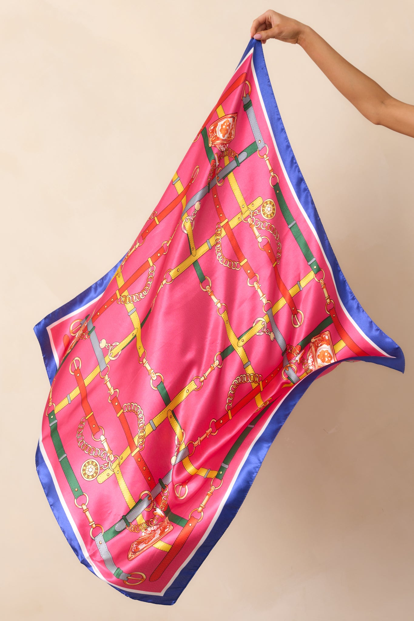 A fuchsia multi-print satin scarf showcasing a stylish chain handbag strap print, highlighted by pops of orange, red, white, and navy. The smooth fabric adds a luxurious touch to the colorful design.