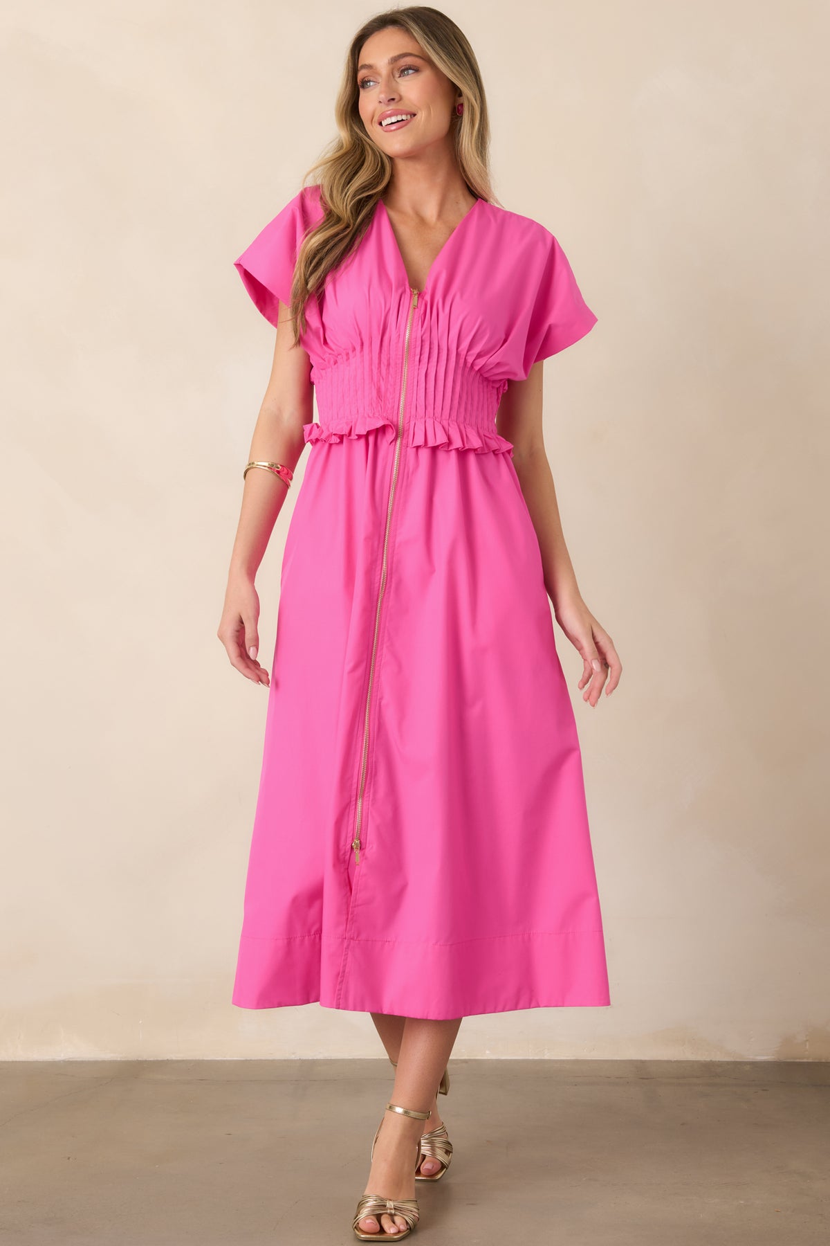 Fuchsia woven dress with a streamlined V-neck bodice, front zipper, defined ruffled waistband, and full-length A-line skirt.