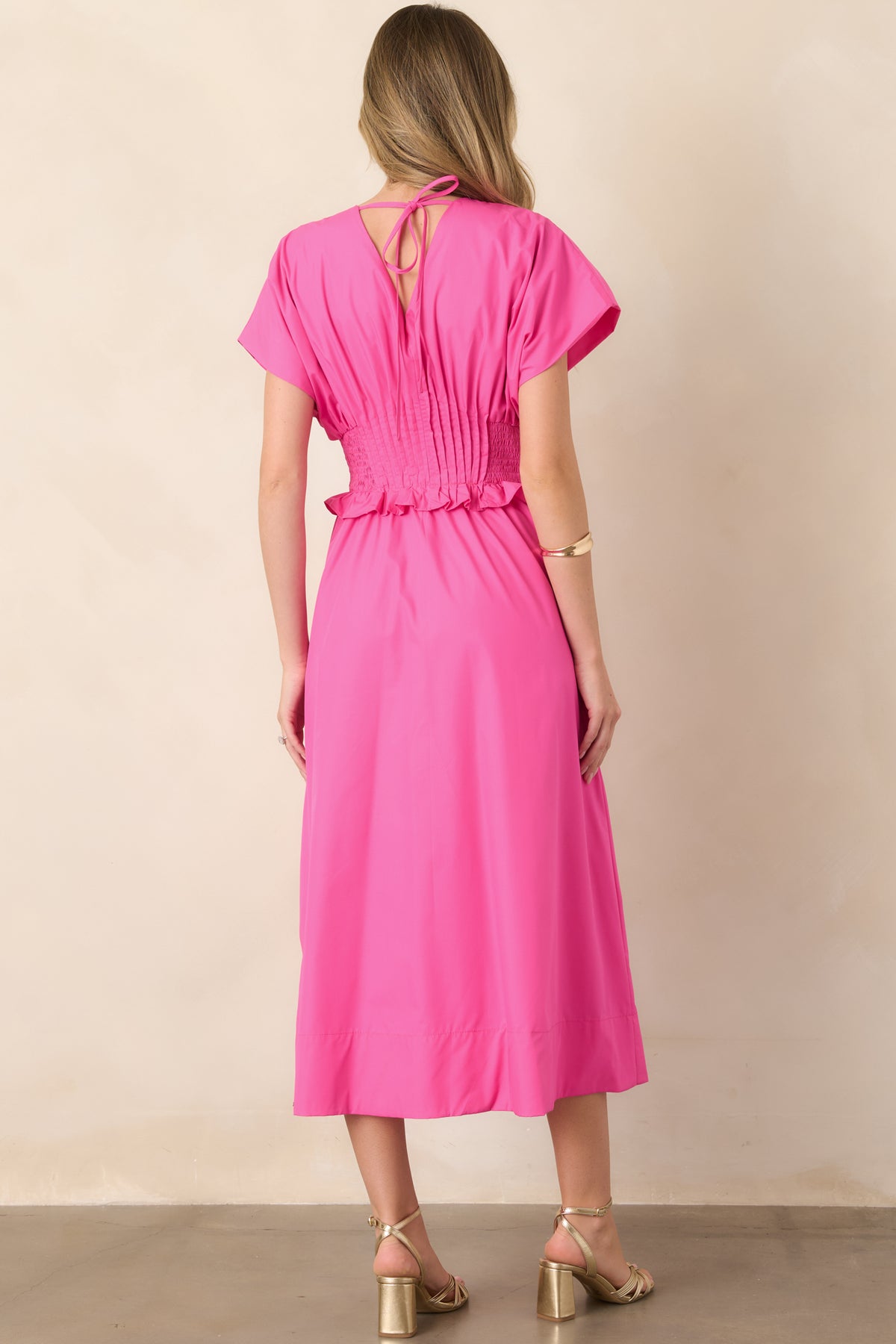 Rear view of the fuchsia woven maxi dress, highlighting the relaxed A-line shape, short sleeves, wide smocked waistband, and full-length skirt.