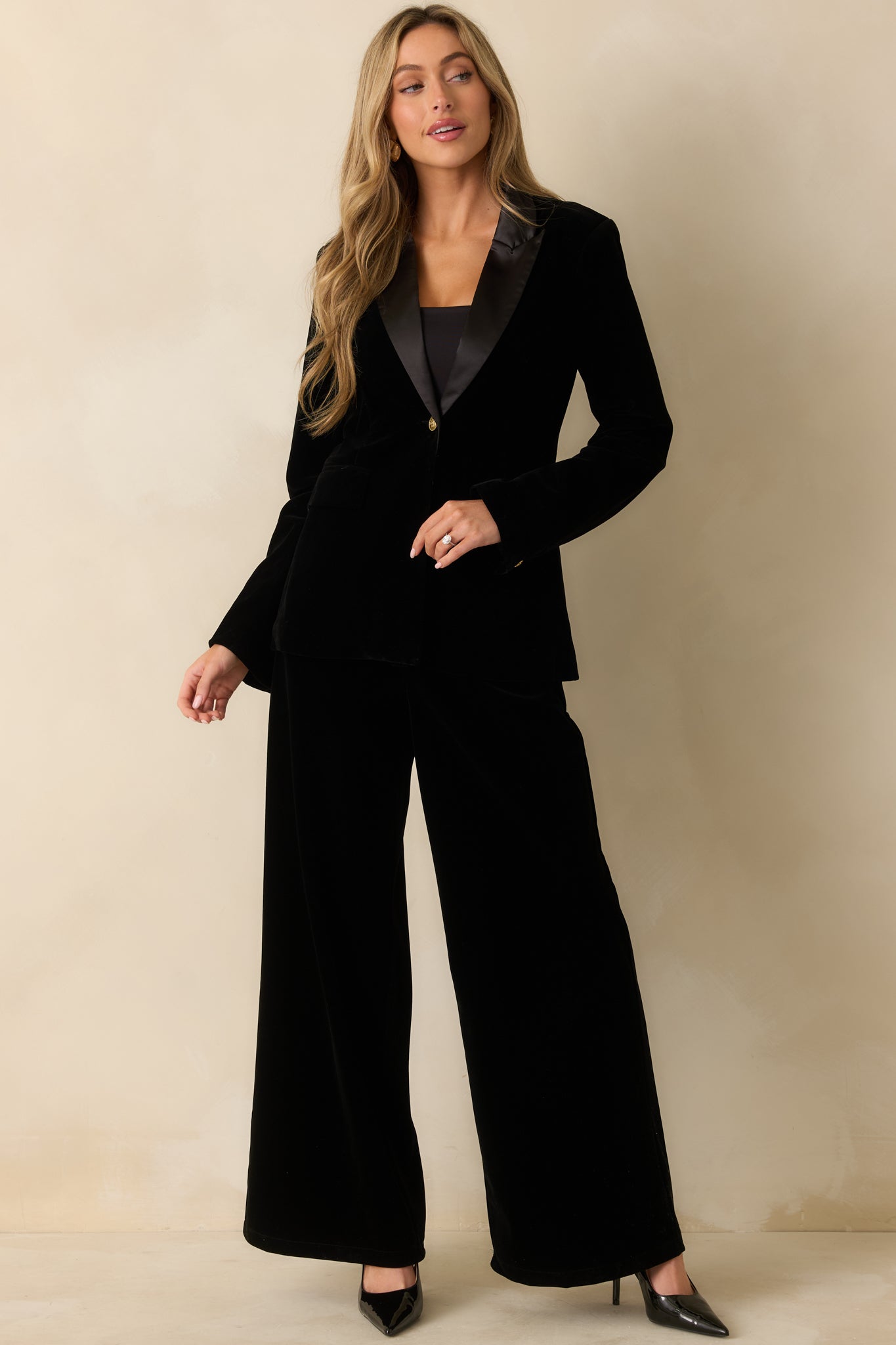 A full-body front view showing the smooth tailored fit and front flap pockets of the velvet blazer.