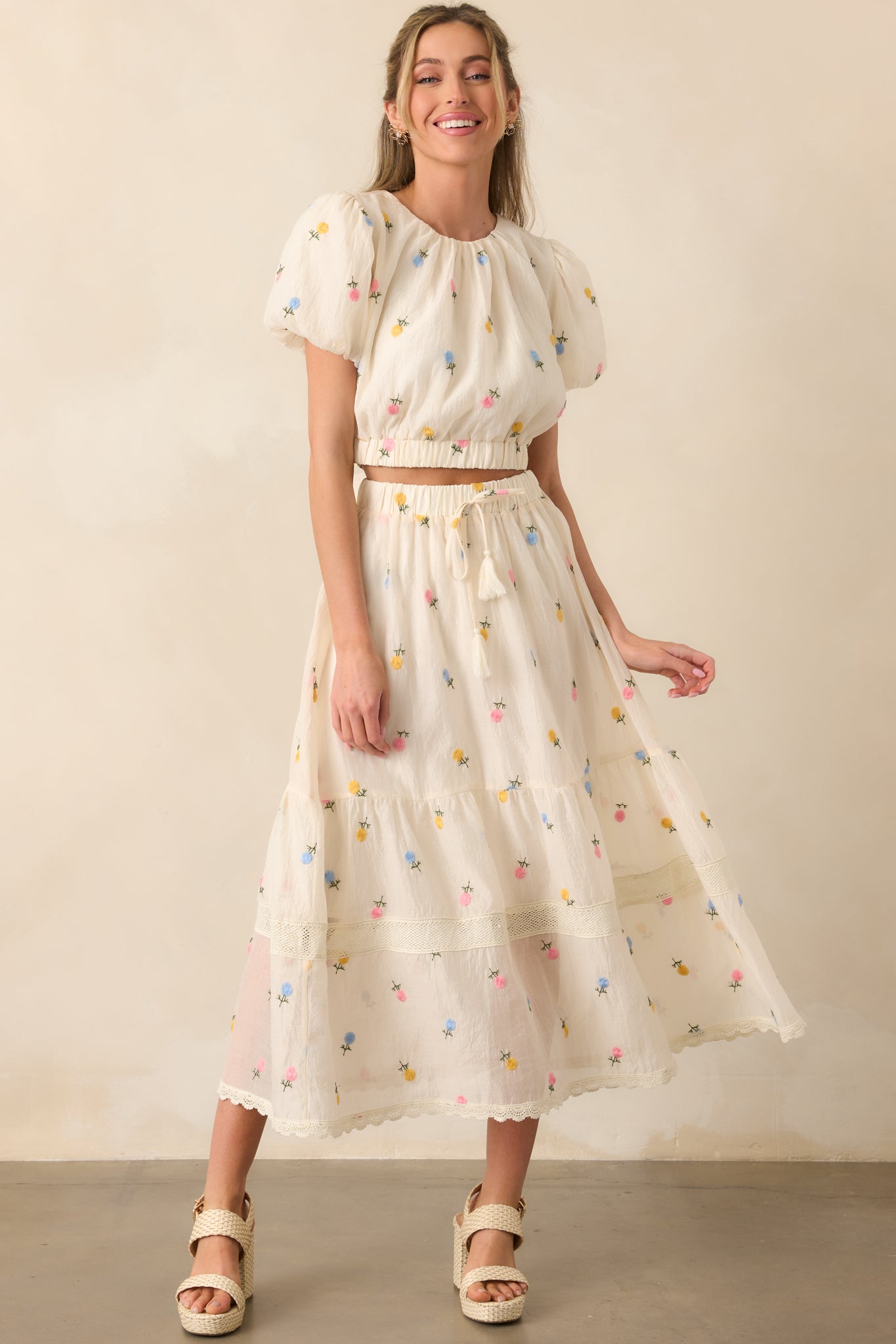 Angled full body shot showing the puff sleeves, round neckline, and elastic waist detail of the embroidered top.