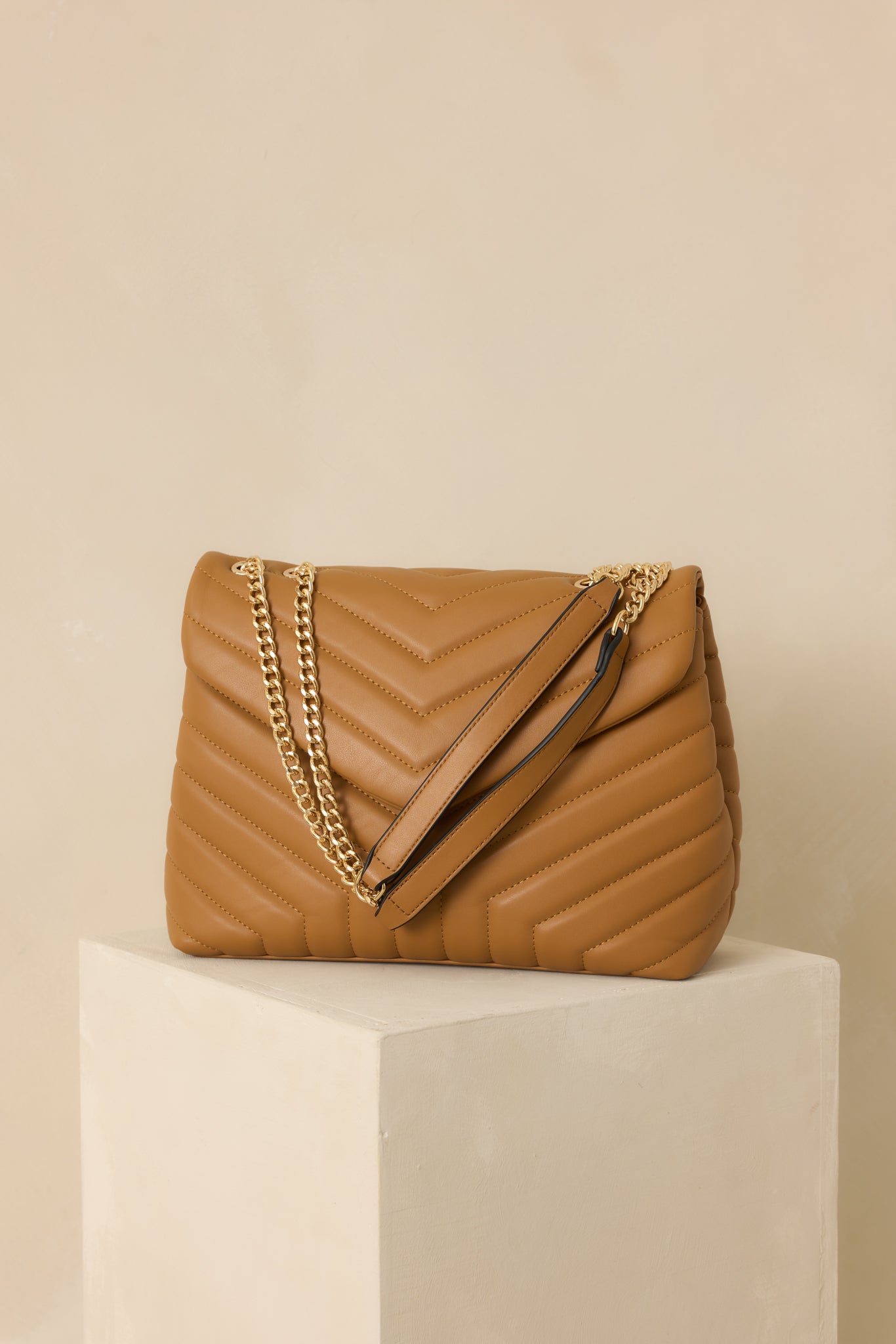 A full front shot highlighting the snap flap closure and quilted design of the handbag.