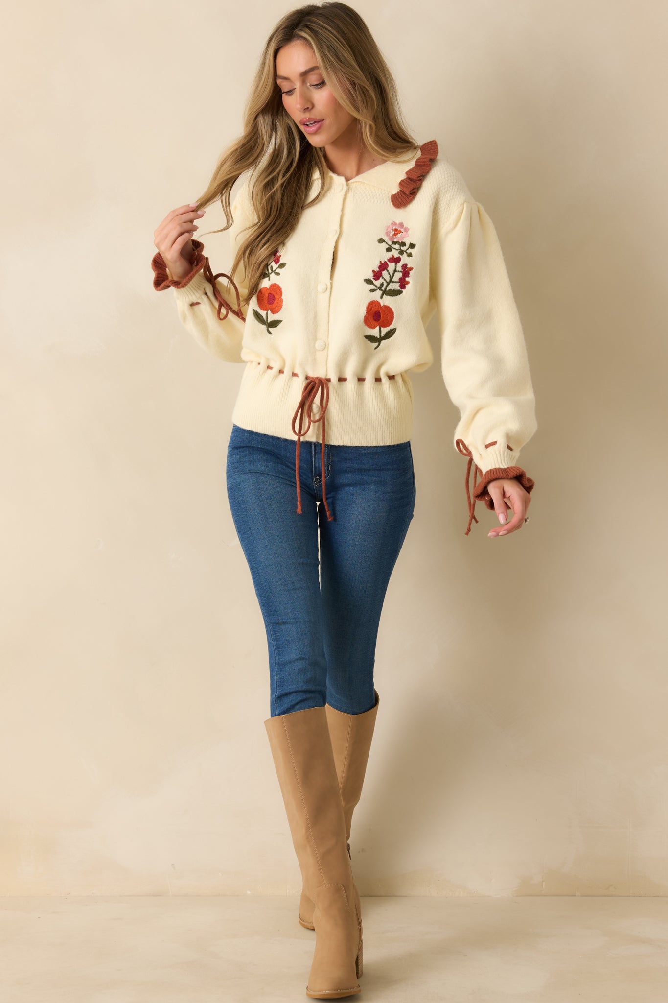 Full-length front view of ivory cardigan showing ruffle-trimmed collar, drawstring waist, and soft knit fabric.