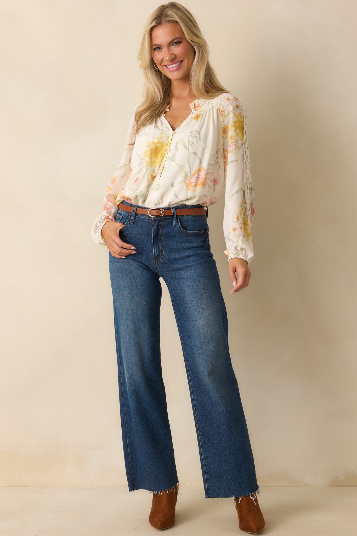 A full front view of the ivory top featuring a yellow multicolor floral print and smocked ruffle neckline.