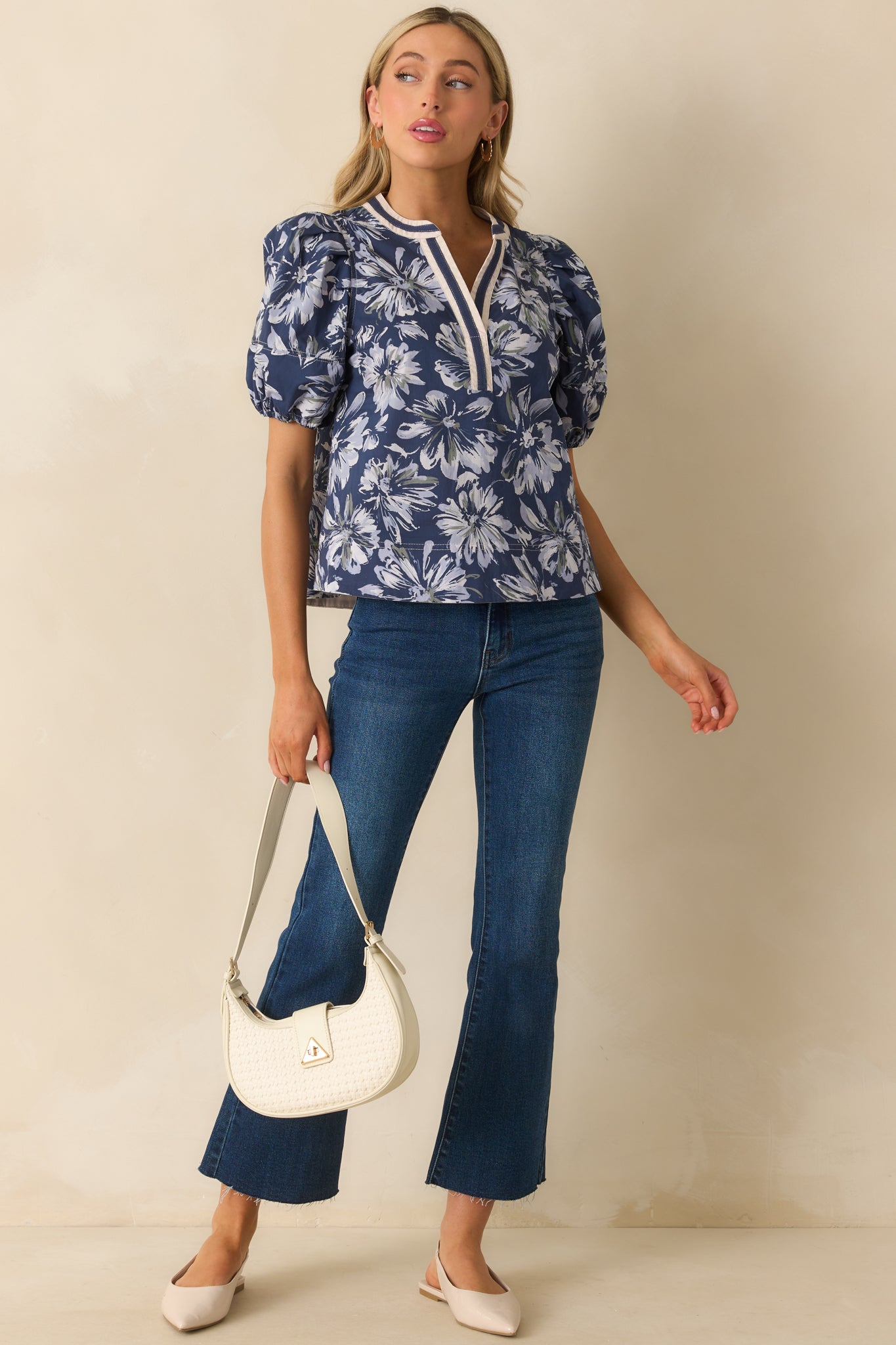 A full front view of the navy top featuring an ivory floral print and notch v-neckline.