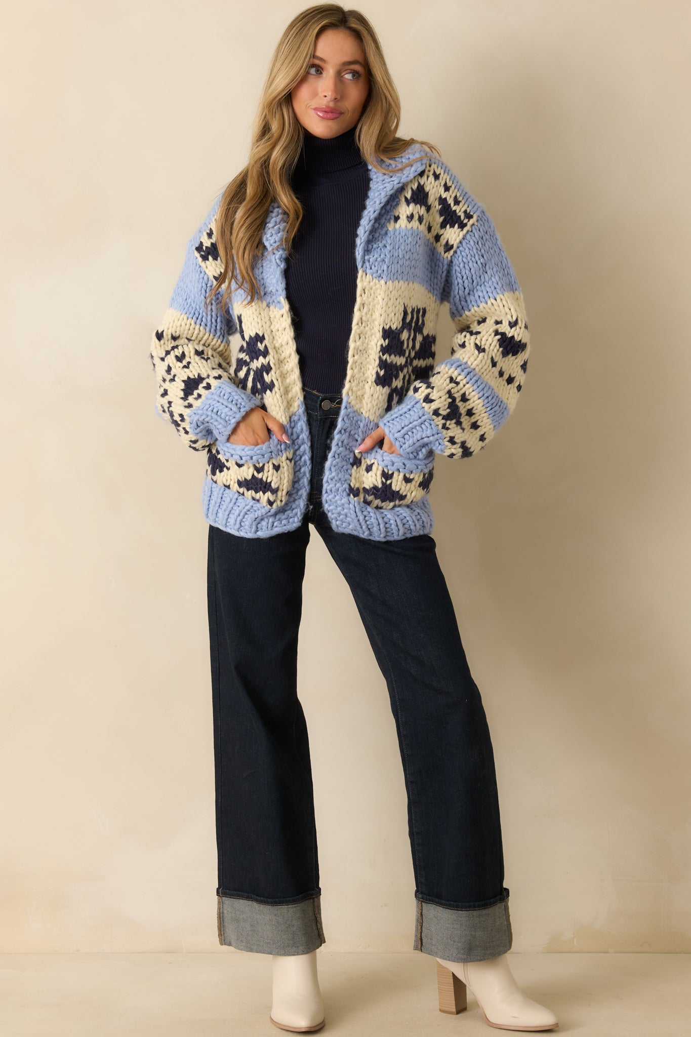 Full-length front view of chunky knit cardigan featuring colorblock pattern in blue, cream, and navy, open front, drop shoulders, and front patch pockets.