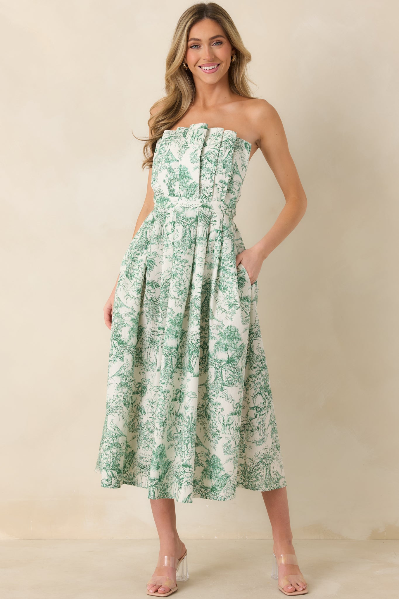 Full-length front view of strapless green midi dress with functional hip pockets and softly pleated skirt.