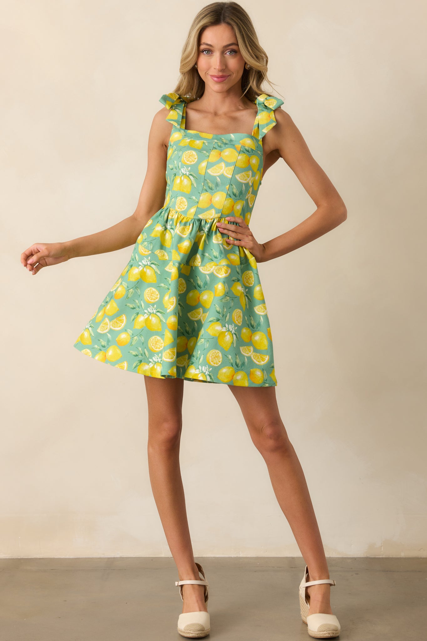 Full length image of the lemon-printed mini dress with a paneled bodice and adjustable self-tie bow straps