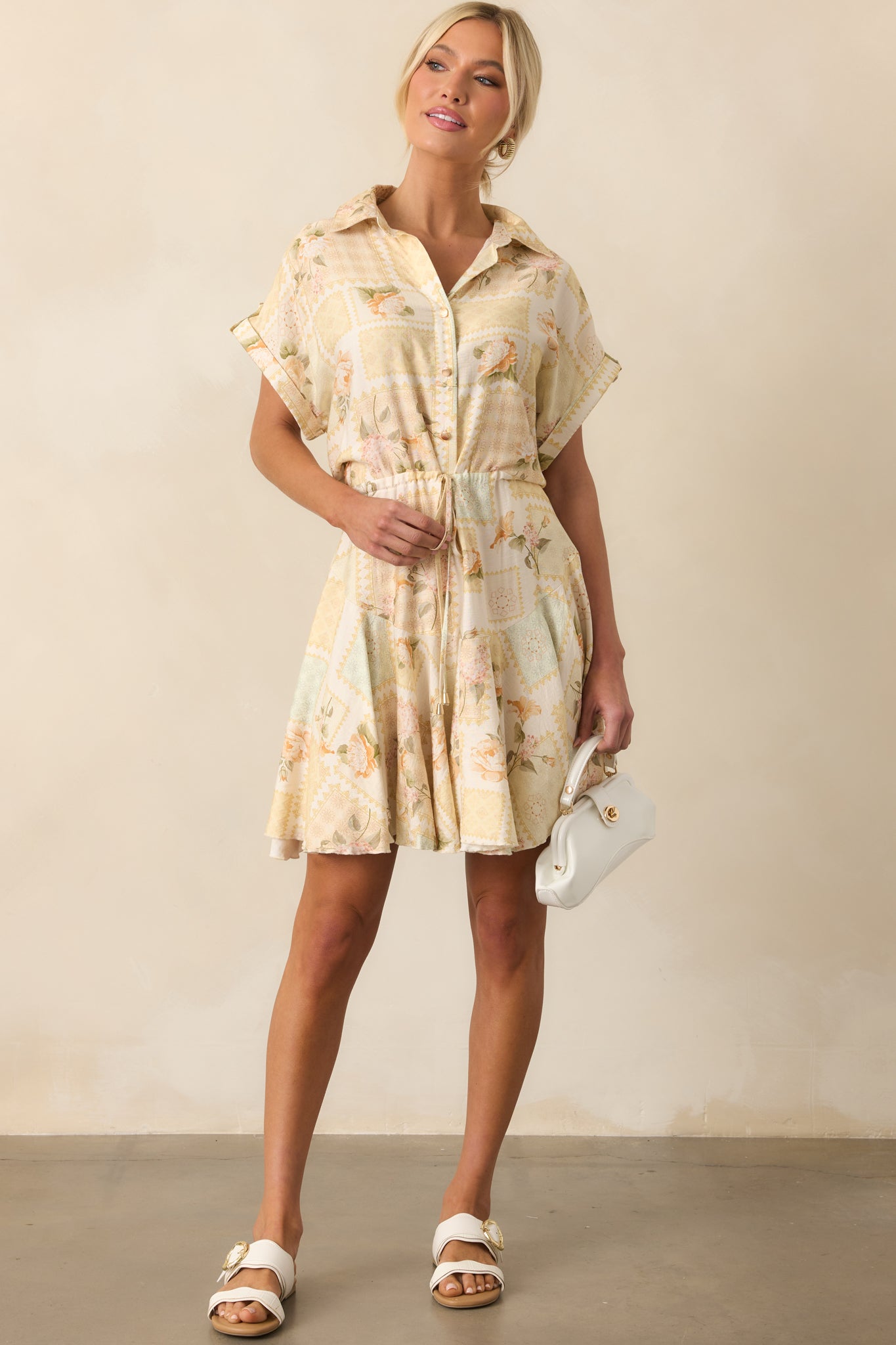 A full length shot showcasing the yellow dress’s structured collar, short cuffed sleeves, and adjustable waist tie.