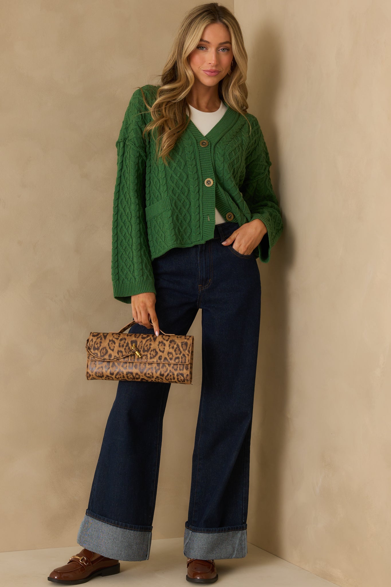 Full view of the forest green cardigan showing the cable knit texture, v-neckline, and functional button front.