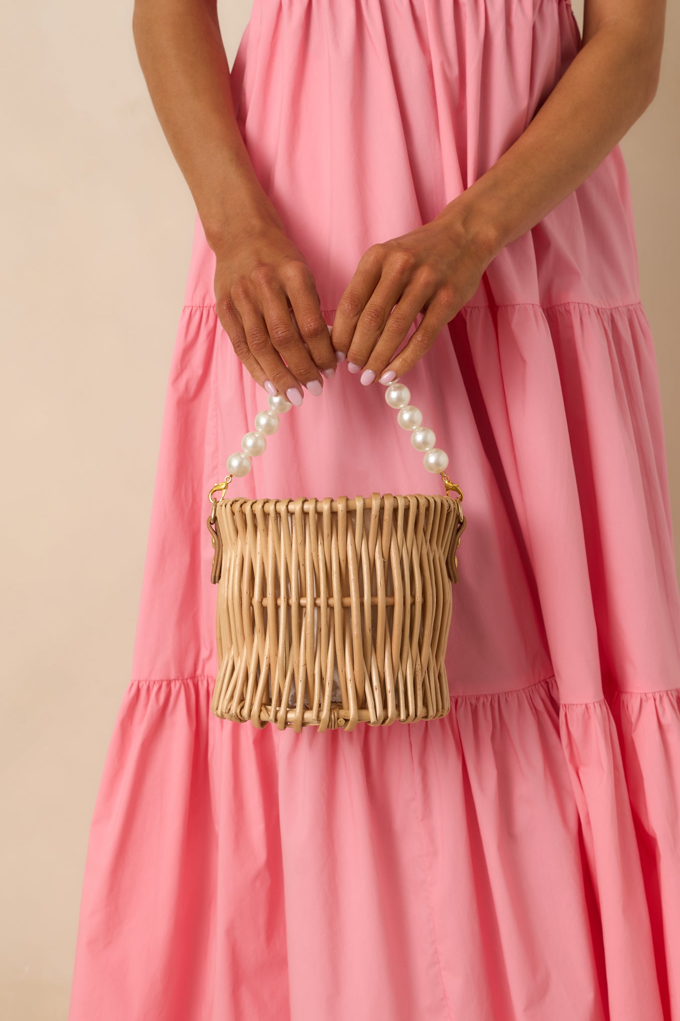 Full view of handbag showcasing wicker design, gold hardware, and removable faux pearl strap.