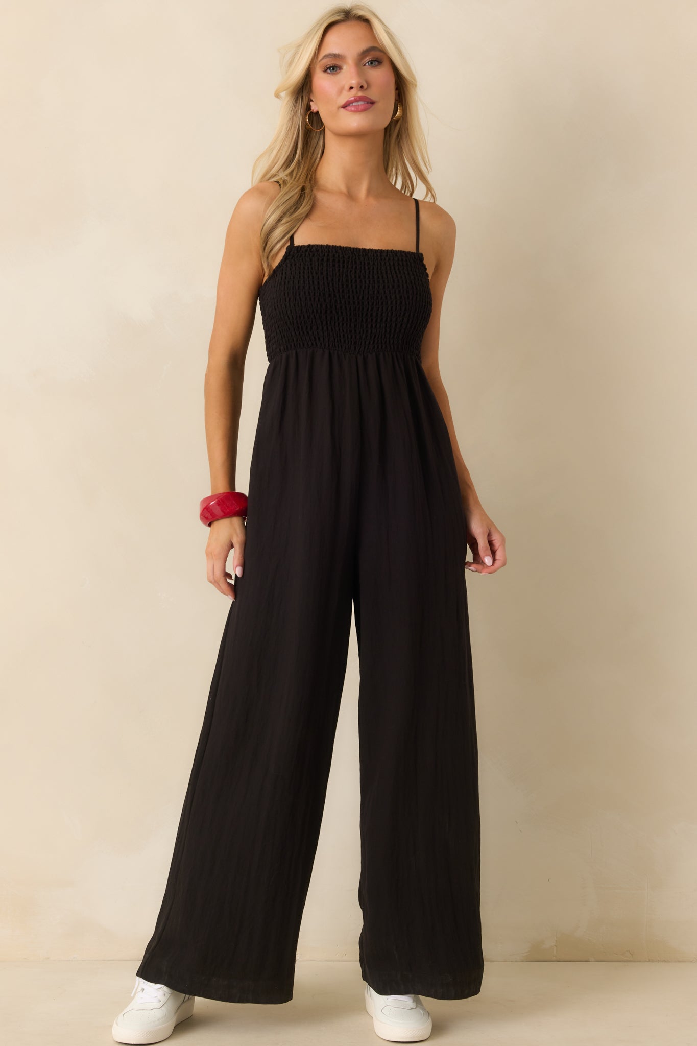 Full body front view highlighting the ivory lining beneath the black jumpsuit’s wide-leg design.