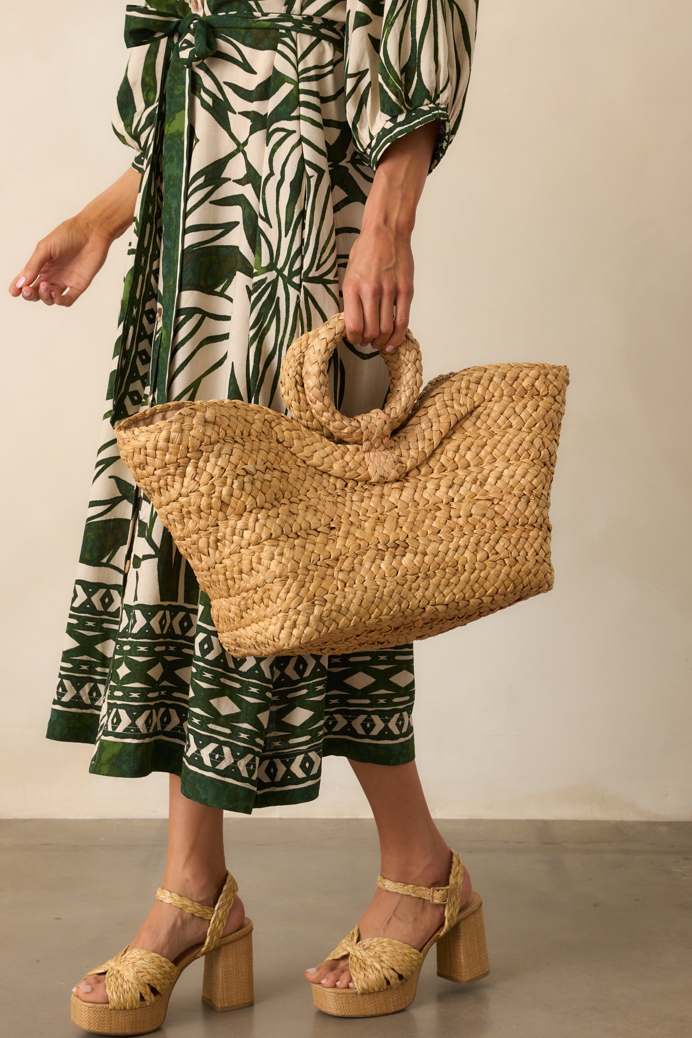 Full body angled view highlighting the structure of the tote and the natural woven texture of the raffia exterior.