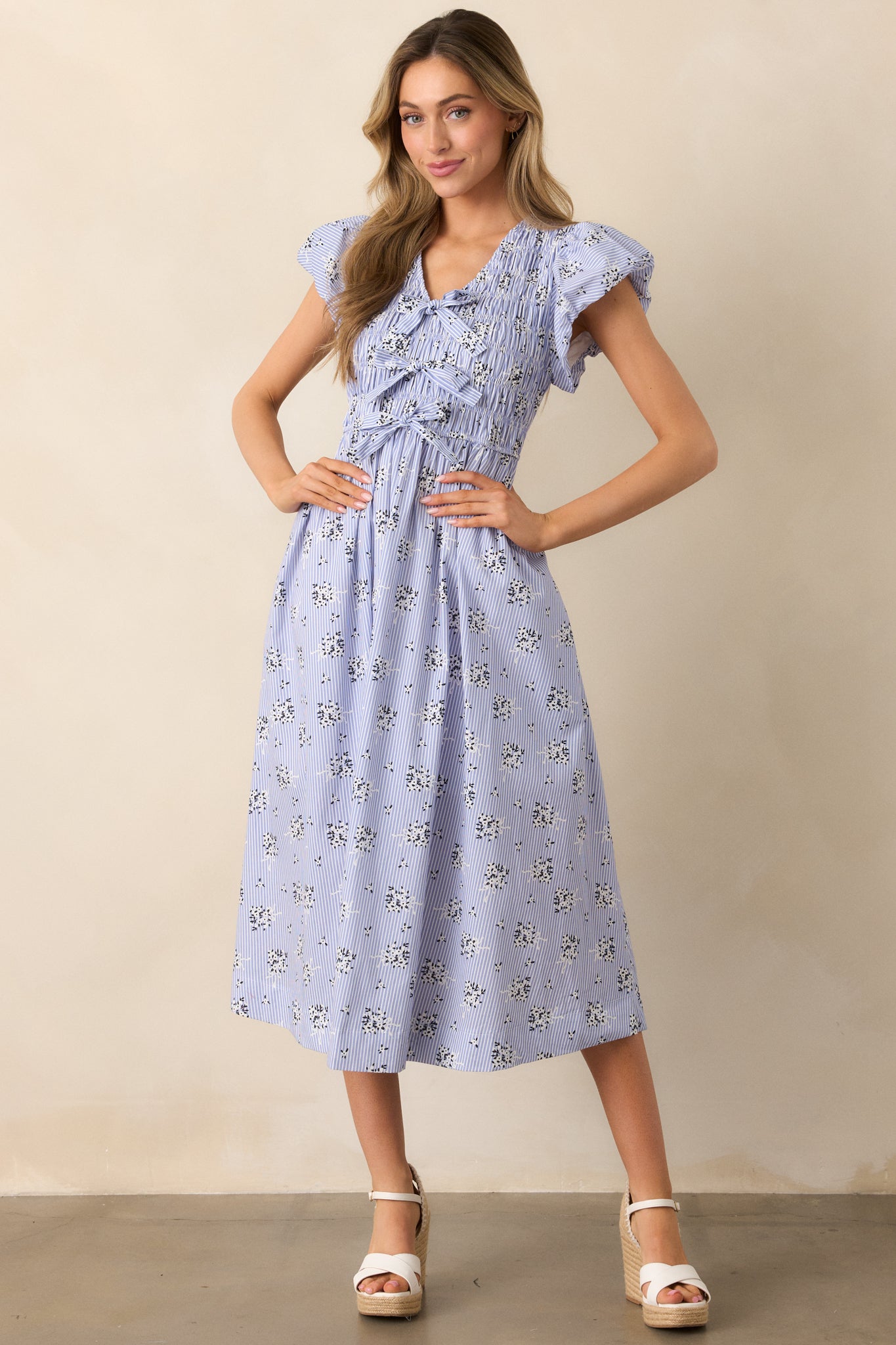 Full view of a blue dress featuring three self-tie bows down the front and puff sleeves with soft volume.