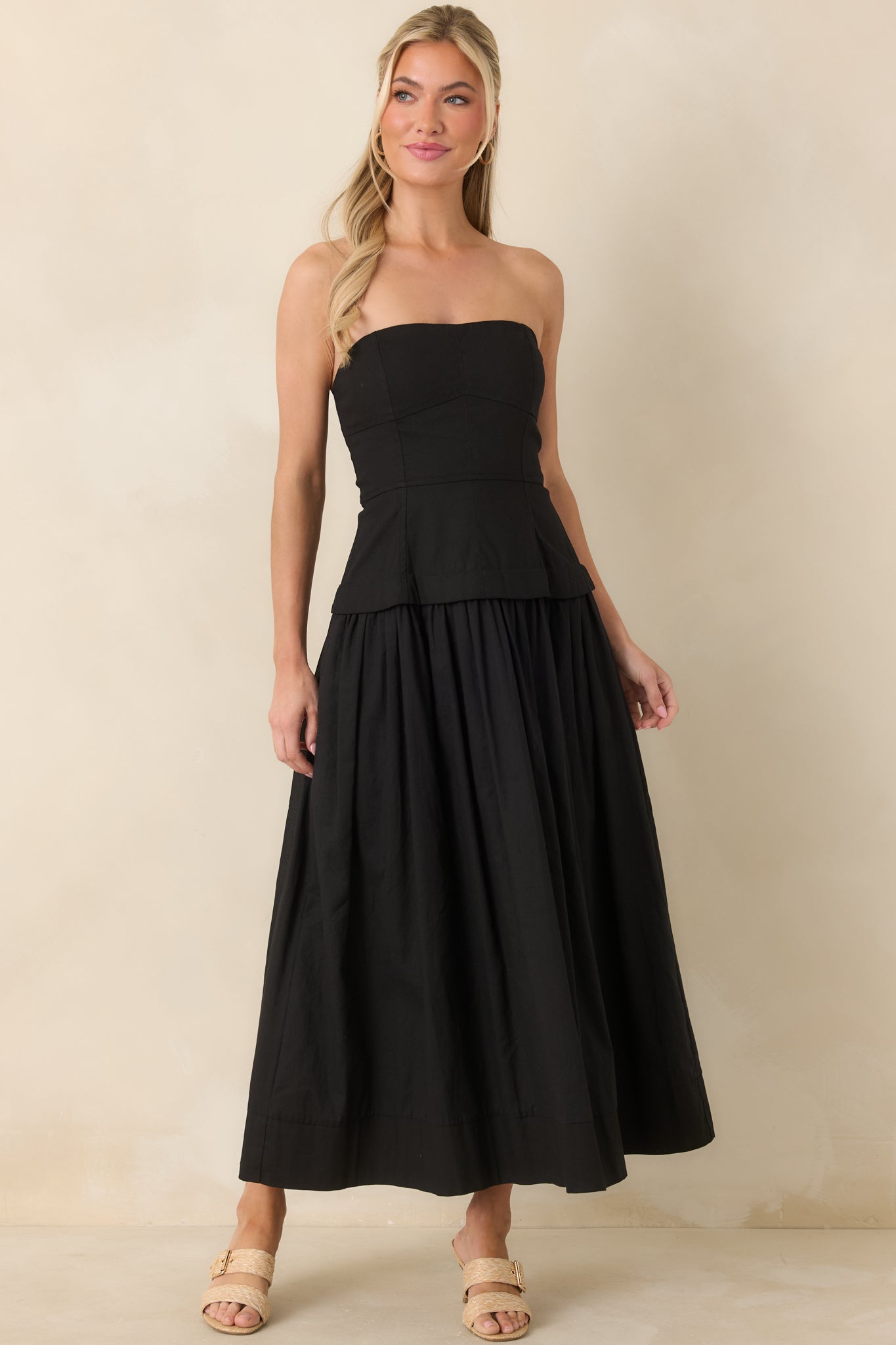 Full view of the black midi dress showcasing the structured bustier bodice and softly gathered skirt with an easy, flowing shape.