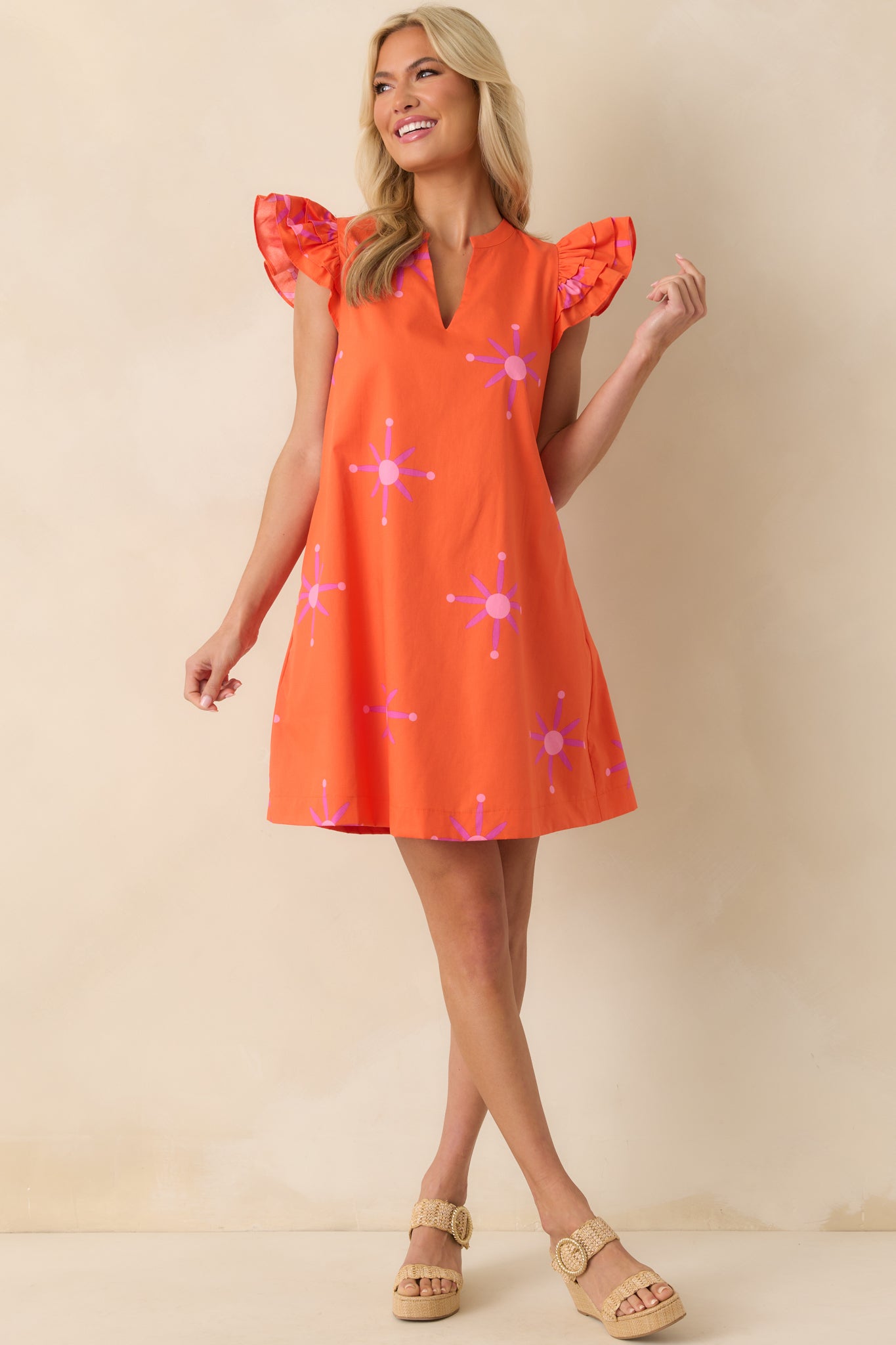 Front-facing full body view of the orange mini dress showcasing the pink floral print and notch v-neckline.