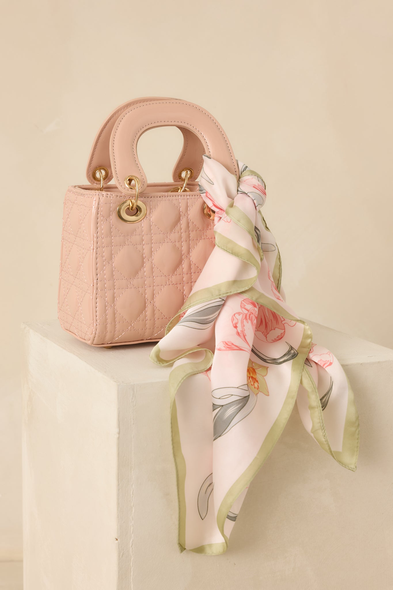 Alternate full view showcasing the light pink quilted handbag with gold-tone ring hardware and flap closure.