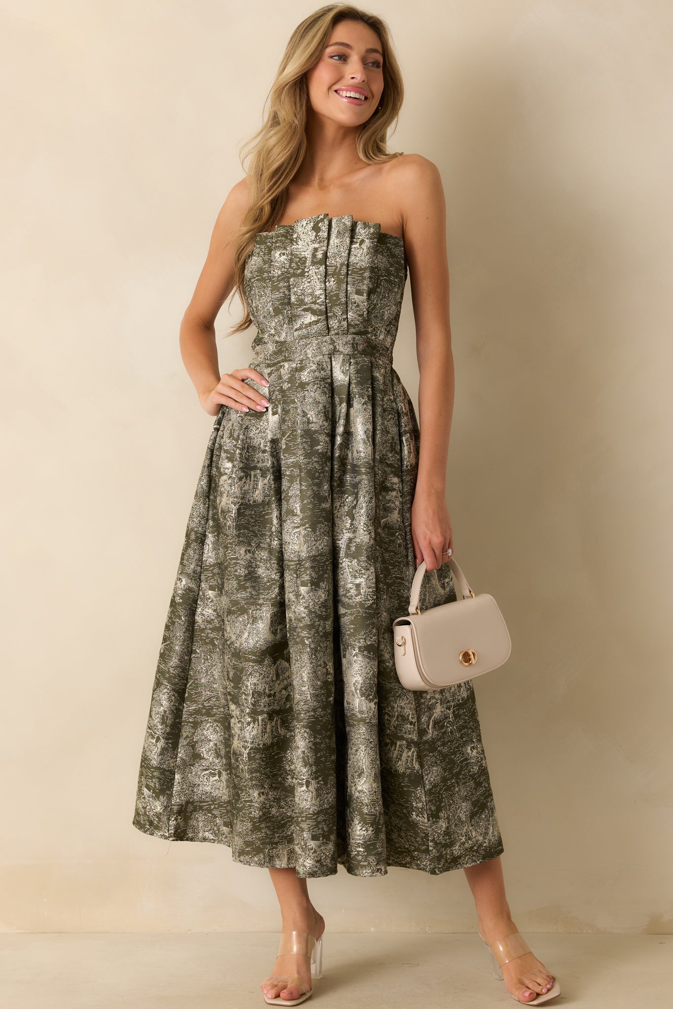 Full-body view of an olive strapless midi dress with an ivory jacquard pattern depicting castle and unicorn motifs.