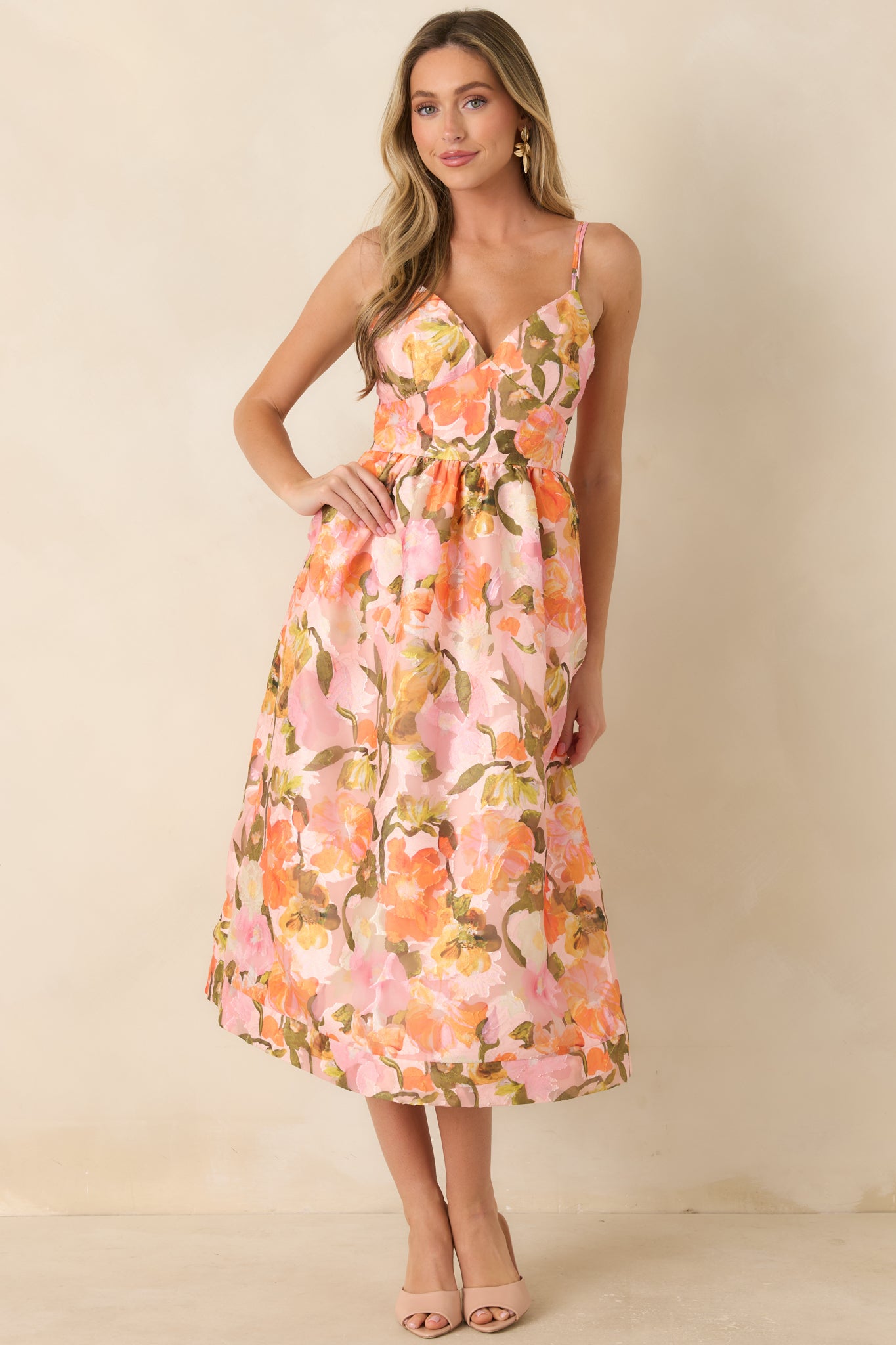 Fully lined floral midi dress with a defined waist, delicate spaghetti straps, and a softly draped skirt in warm pastel hues.