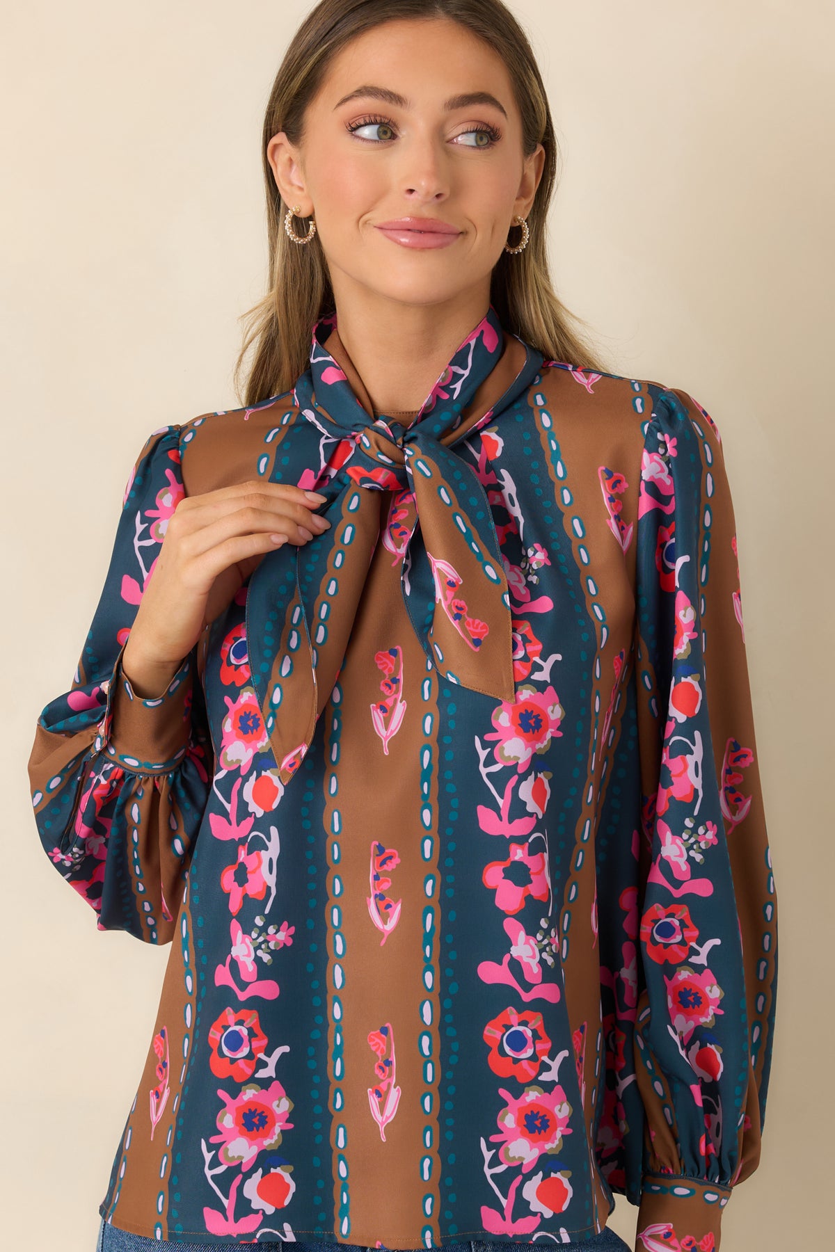 Gathered shoulder seams create gentle volume across the long sleeves of the striped floral blouse.