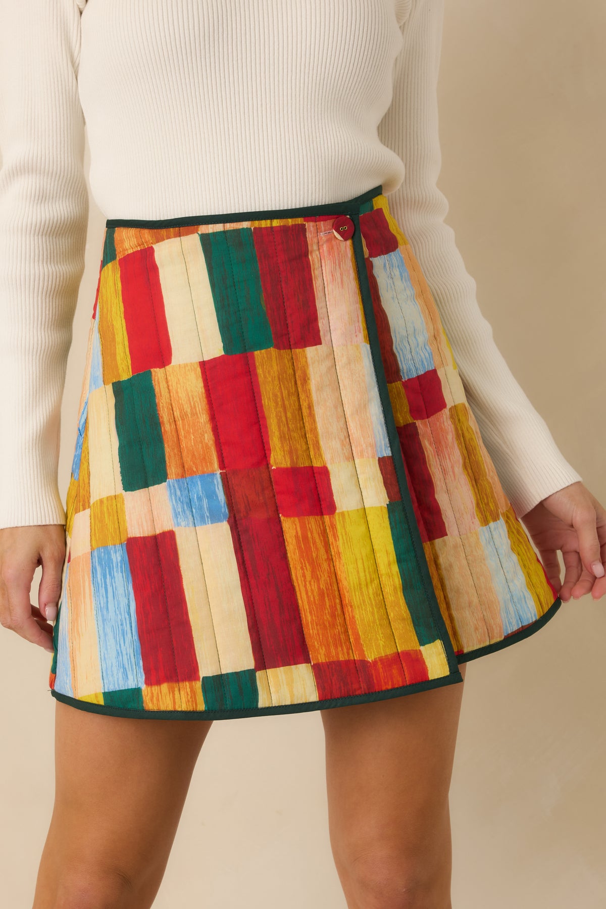 Close-up of the painterly geometric print, quilted stitching, and green binding framing the skirt.