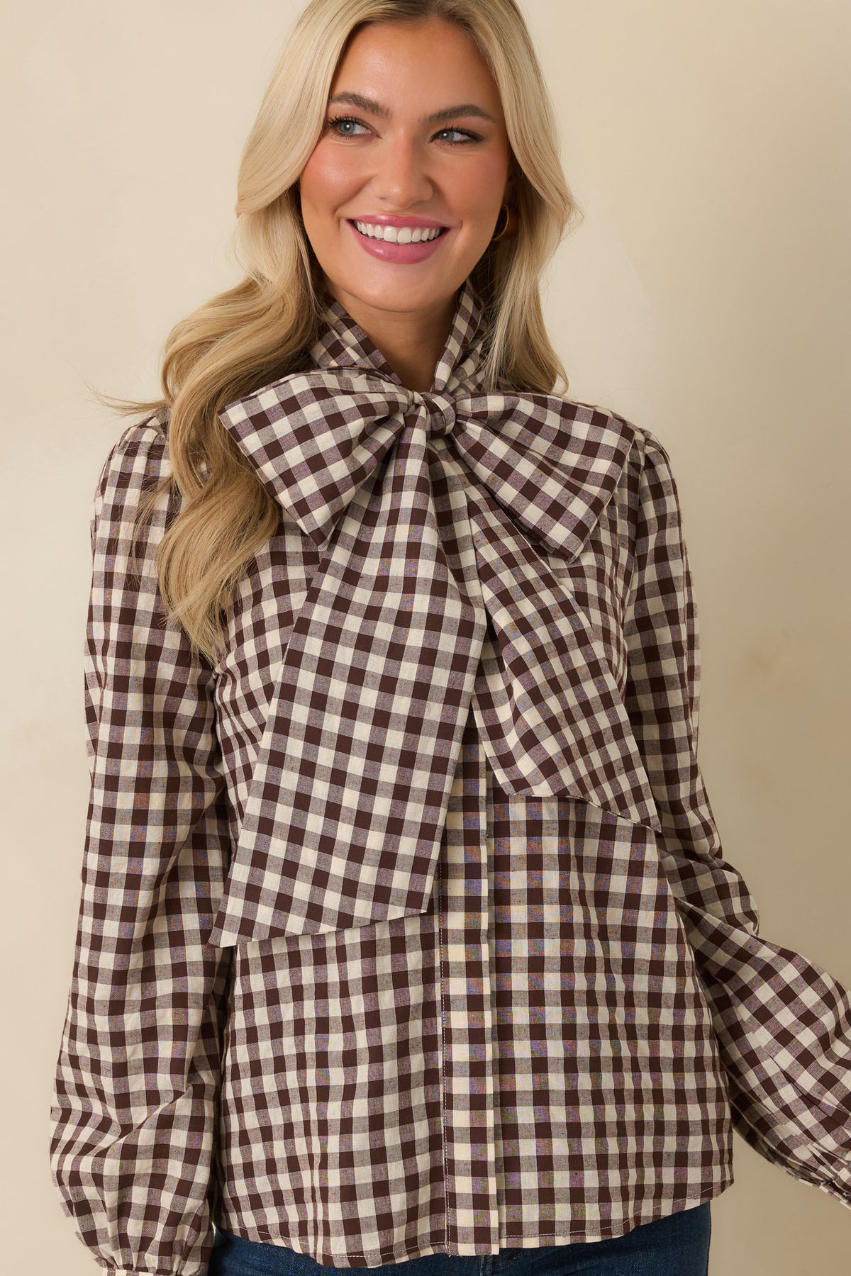 Gingham blouse featuring a removable statement bow, concealed front placket, and long sleeves with buttoned cuffs.