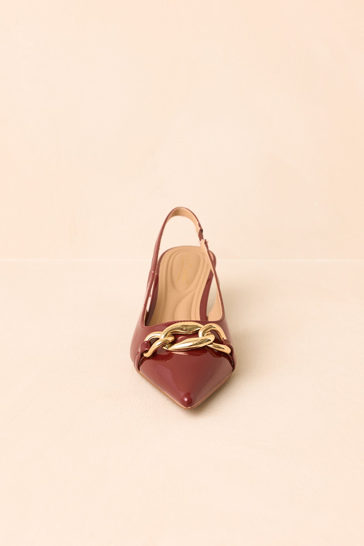Glossy rust-toned heels displaying the oversized chain detail and low heel.