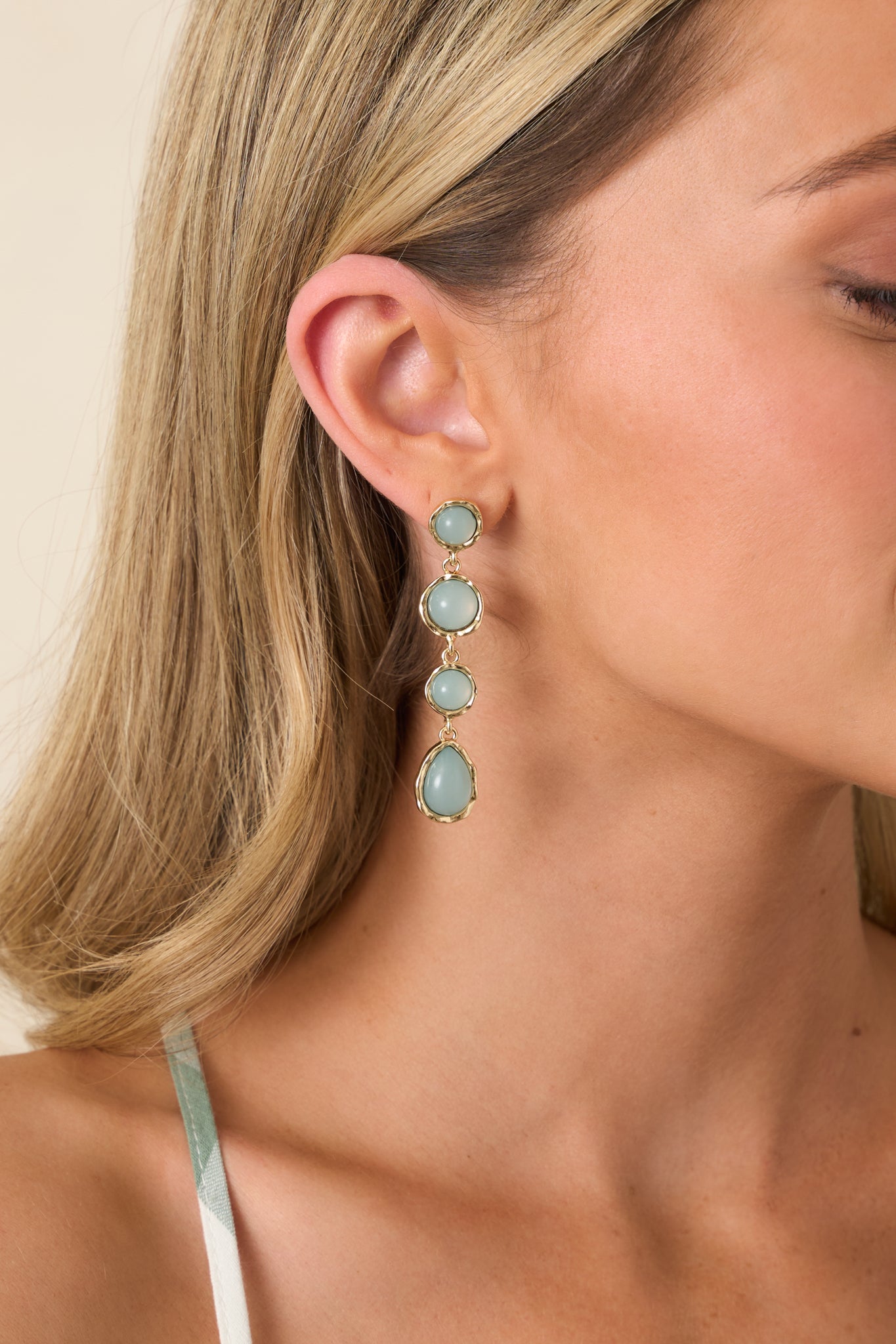 Gold and sage green teardrop earrings with smooth stone framed in polished gold and vertical drop silhouette.