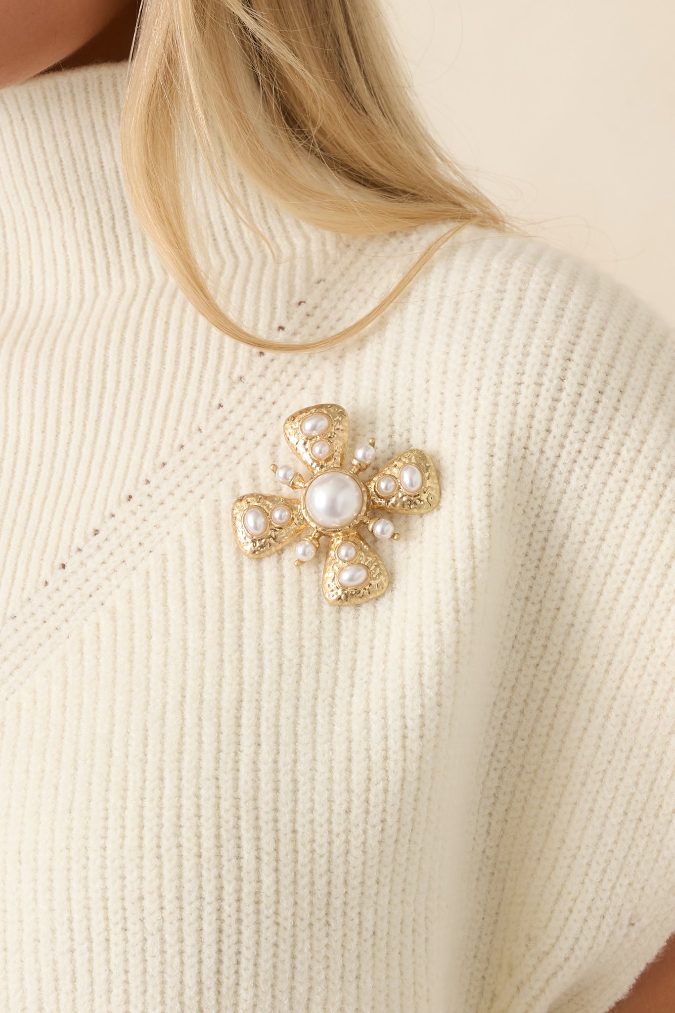 Gold brooch featuring a large faux pearl center, four triangular sections with pearl accents, and a polished vintage-inspired design.
