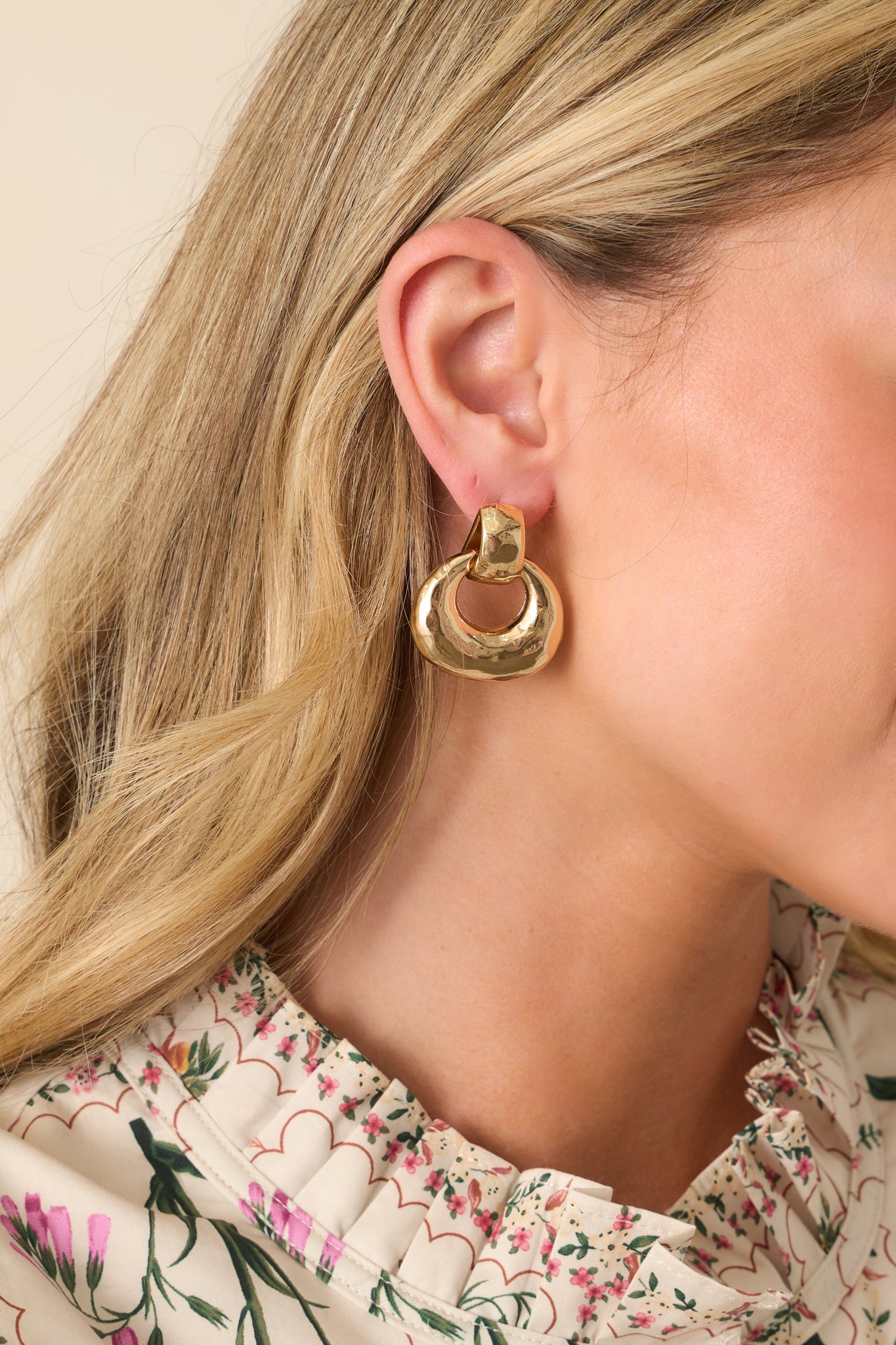 A cropped view of the gold earrings showing the circular drop link hanging from a polished gold stud.
