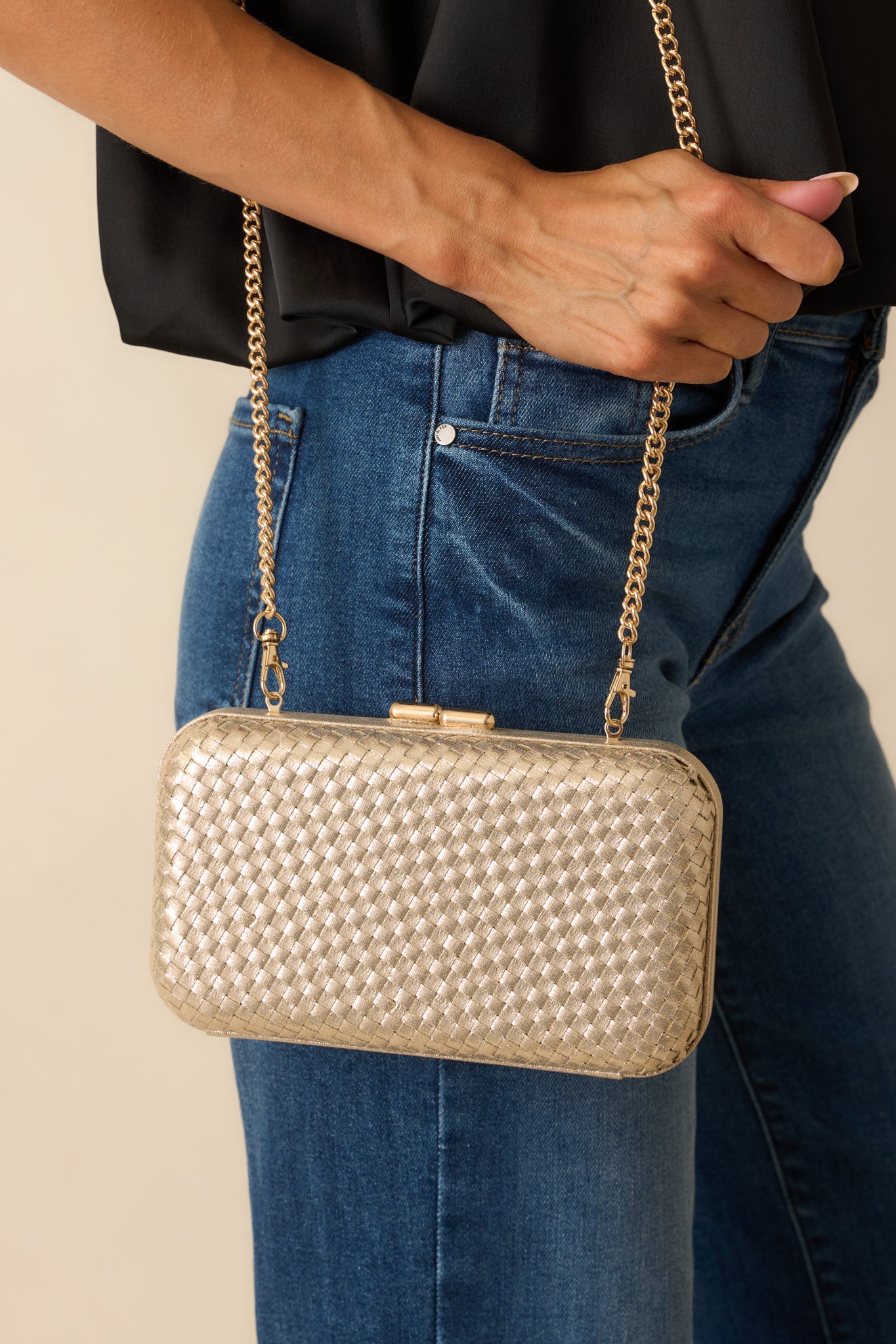 Detailed close-up of the top clasp closure and woven gold surface, showing the hard case construction.