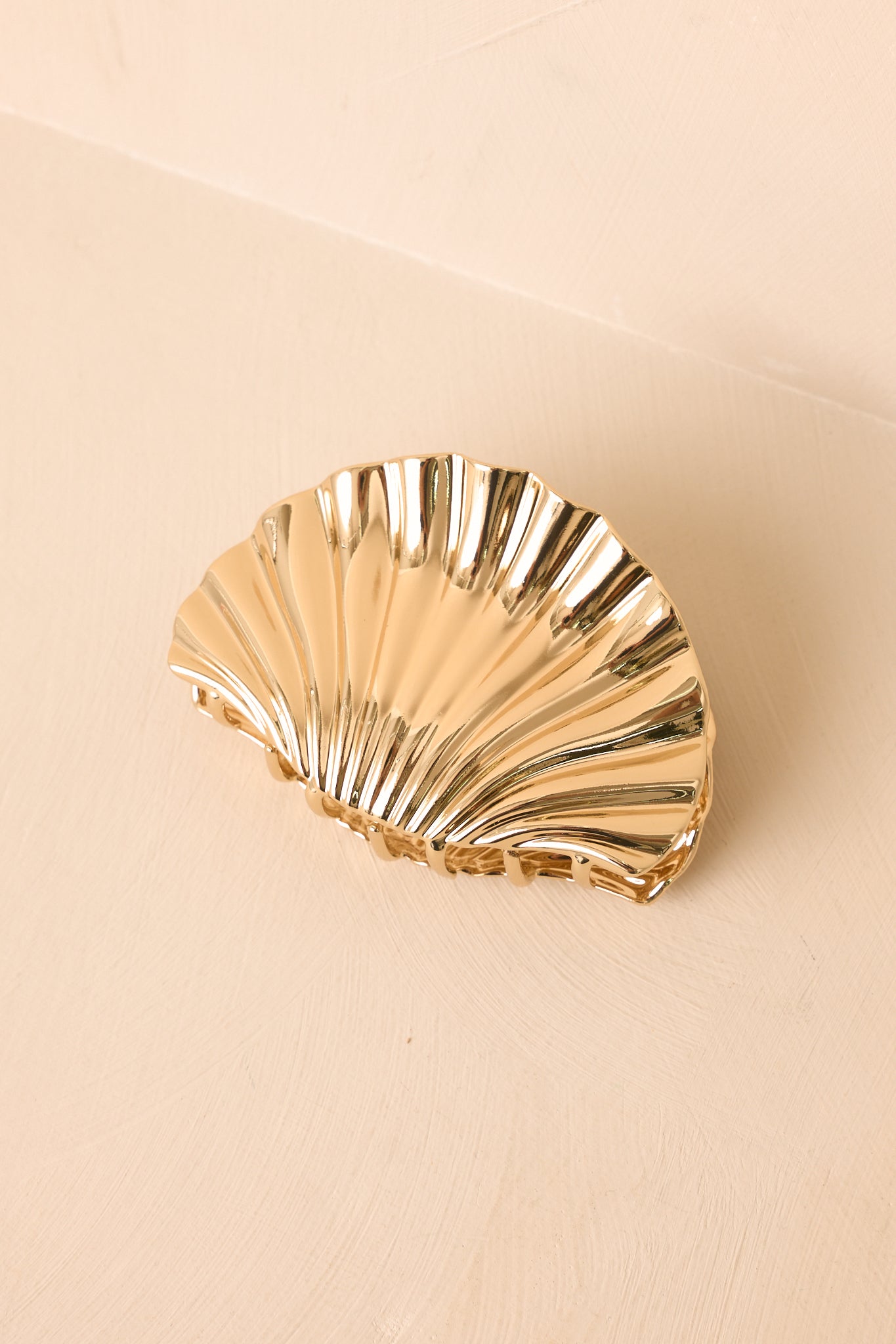 High-shine gold hair clip showcasing a sculptural curved shape and polished everyday accessory design.