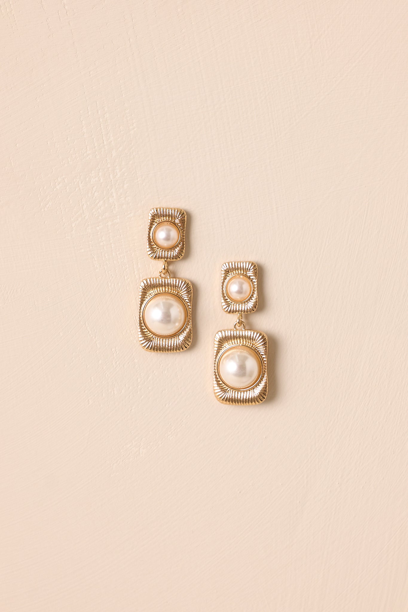 A close-up shot highlighting the double-drop design with small faux pearl in a gold rectangular frame.