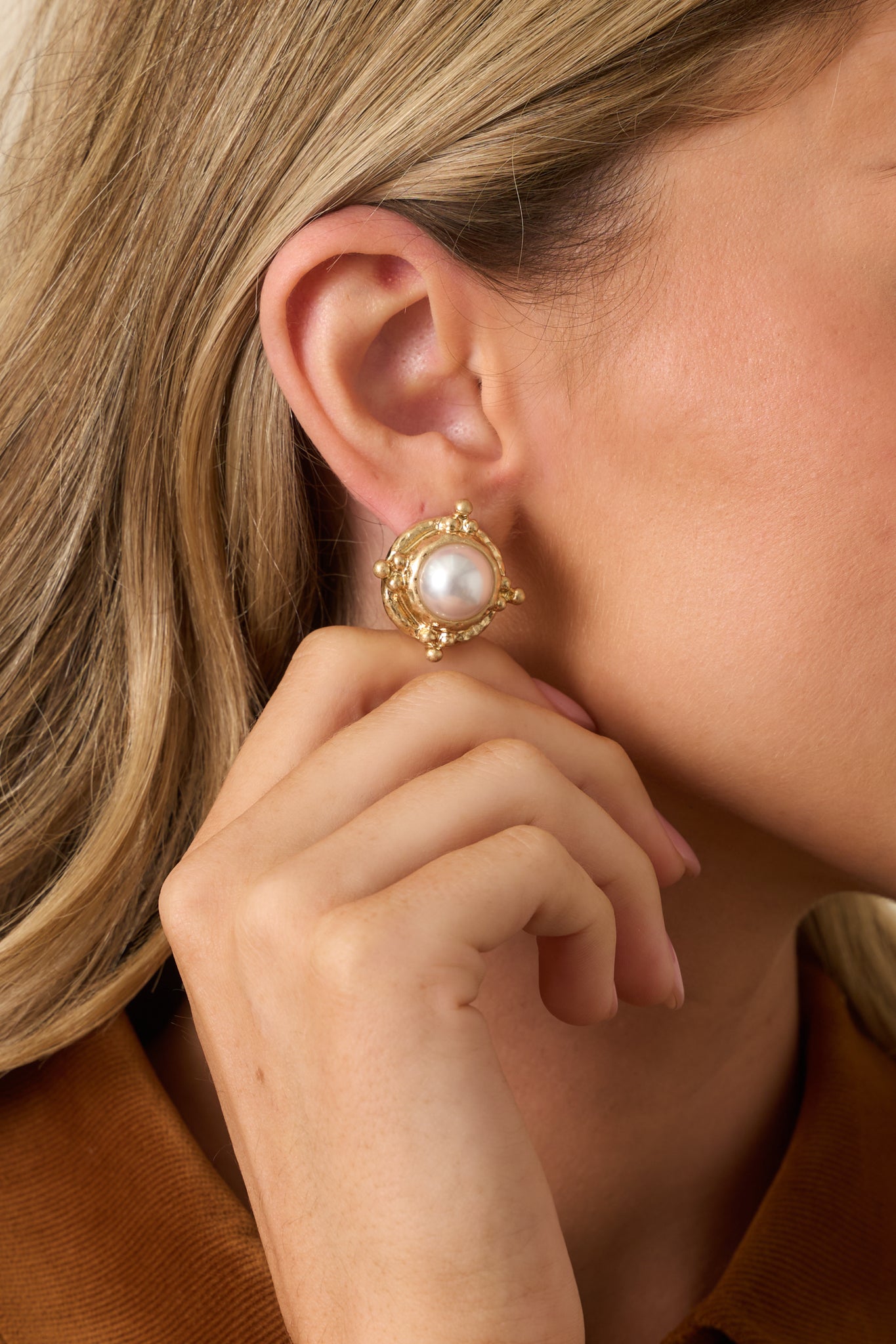 Cropped shot highlighting circular gold frame and central pearl detail.