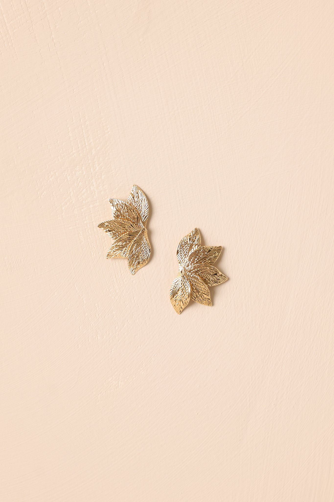 Gold earrings featuring a leaf-shaped design with polished gold hardware shown from the front.