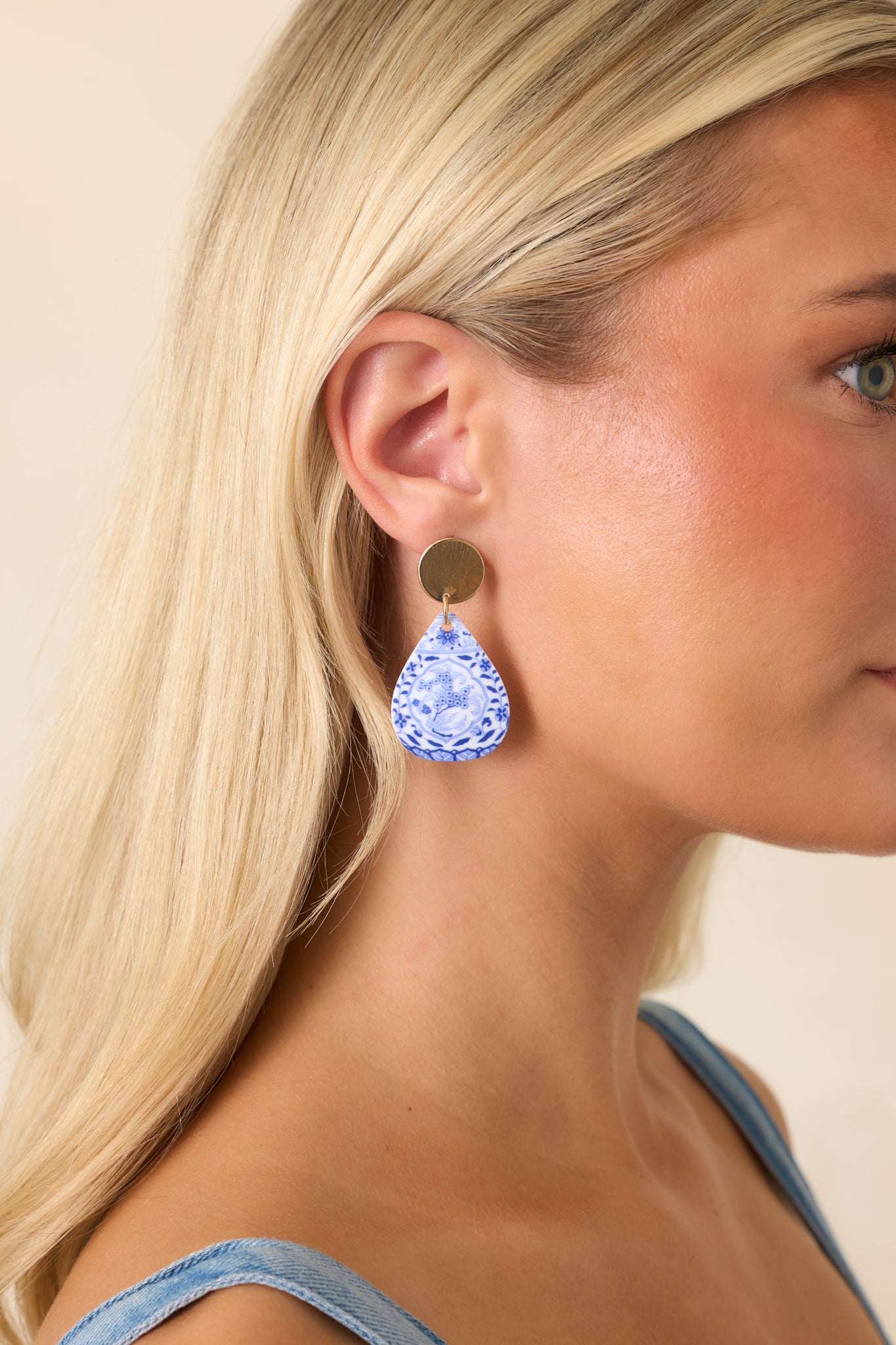 Gold-tone teardrop earrings featuring textured floral motifs with elegant stud tops and a lightweight statement design.
