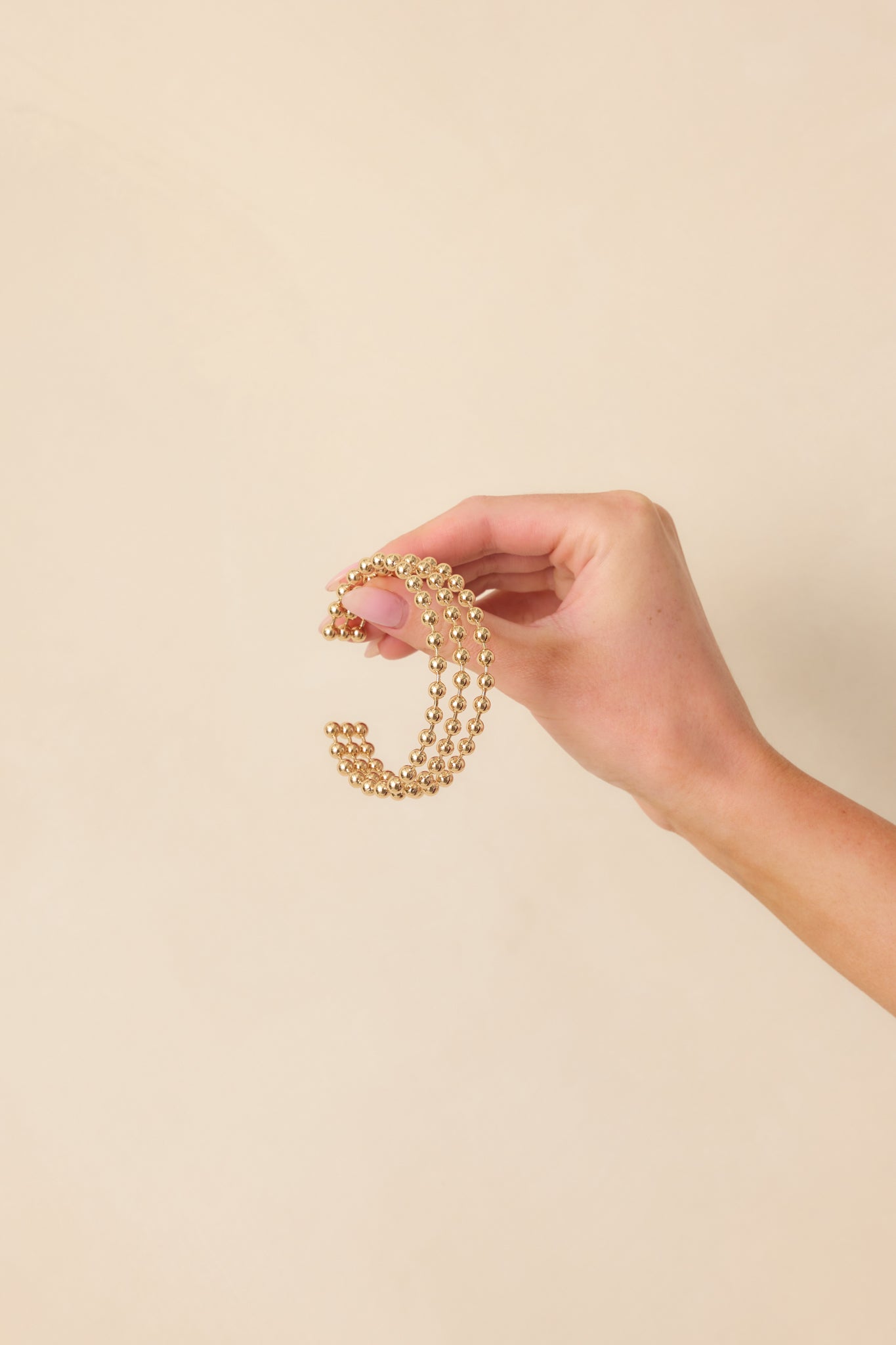 A cropped image showing the gold bracelet’s open cuff shape with evenly spaced rounded ball prongs along the band.