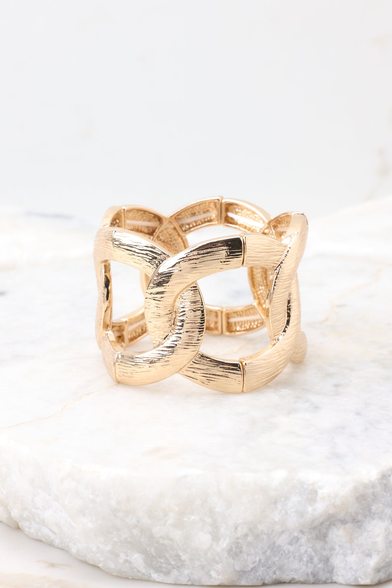 Gold linked bracelet photographed from the side against a white background, showing the thickness and rounded profile of the links.