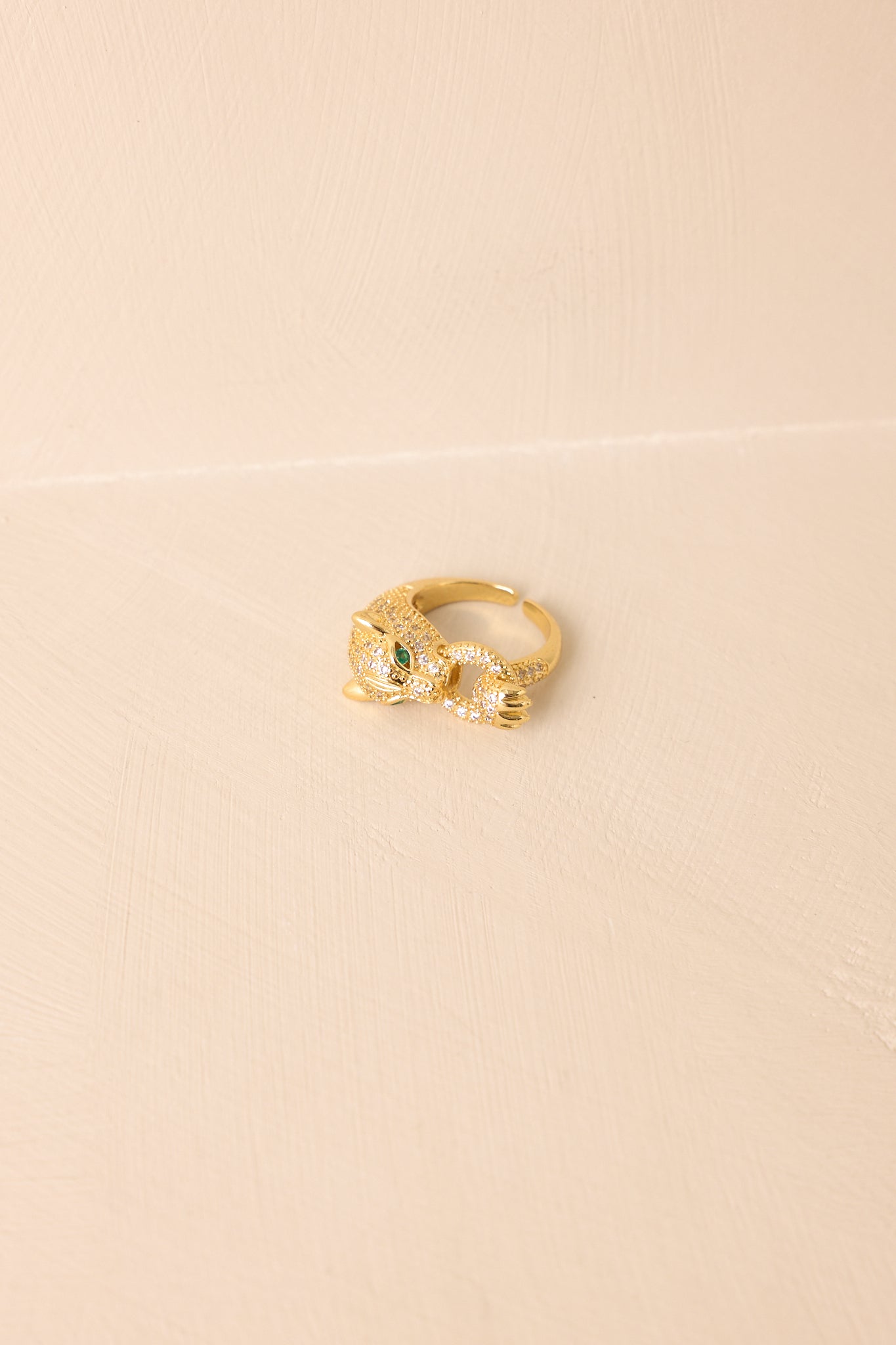Gold Panther Head Pavé Ring displayed on a beige background, showcasing the wrap-around open band and rhinestone detailing.