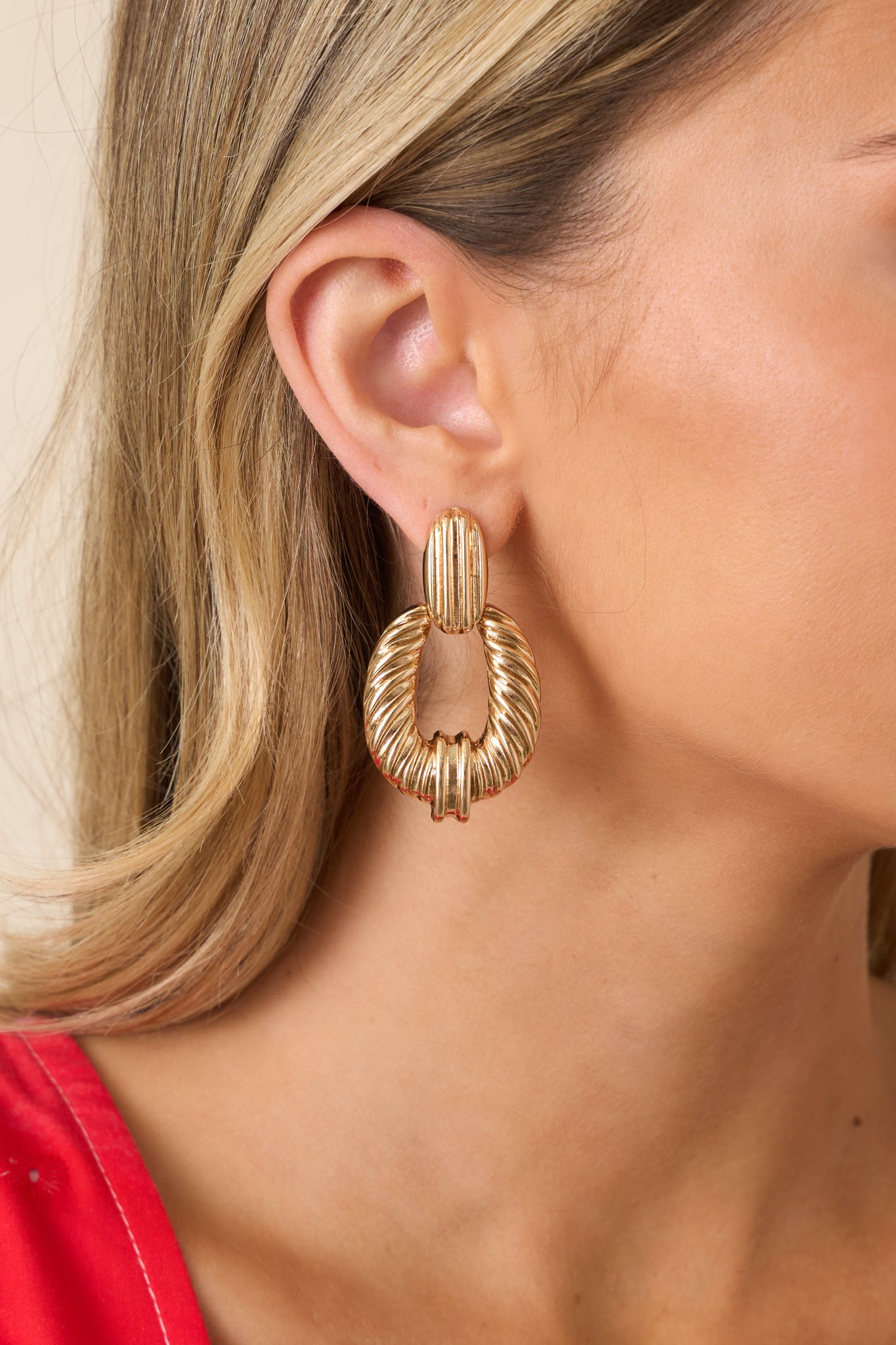 Gold earrings featuring rectangular stud tops, textured dangling details, and secure post backings for a statement look