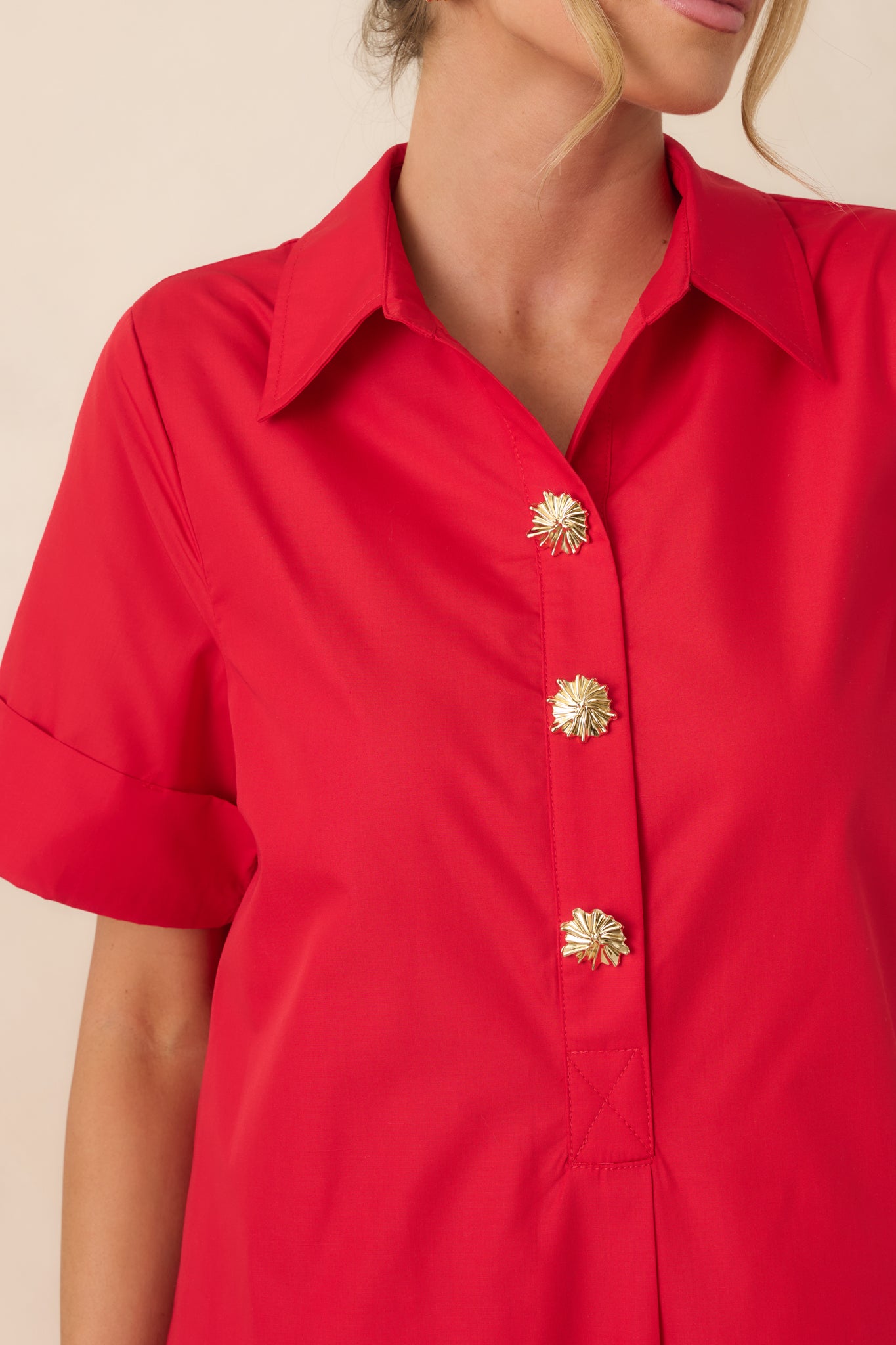 Gold snap buttons and collar detail on vibrant red fabric.