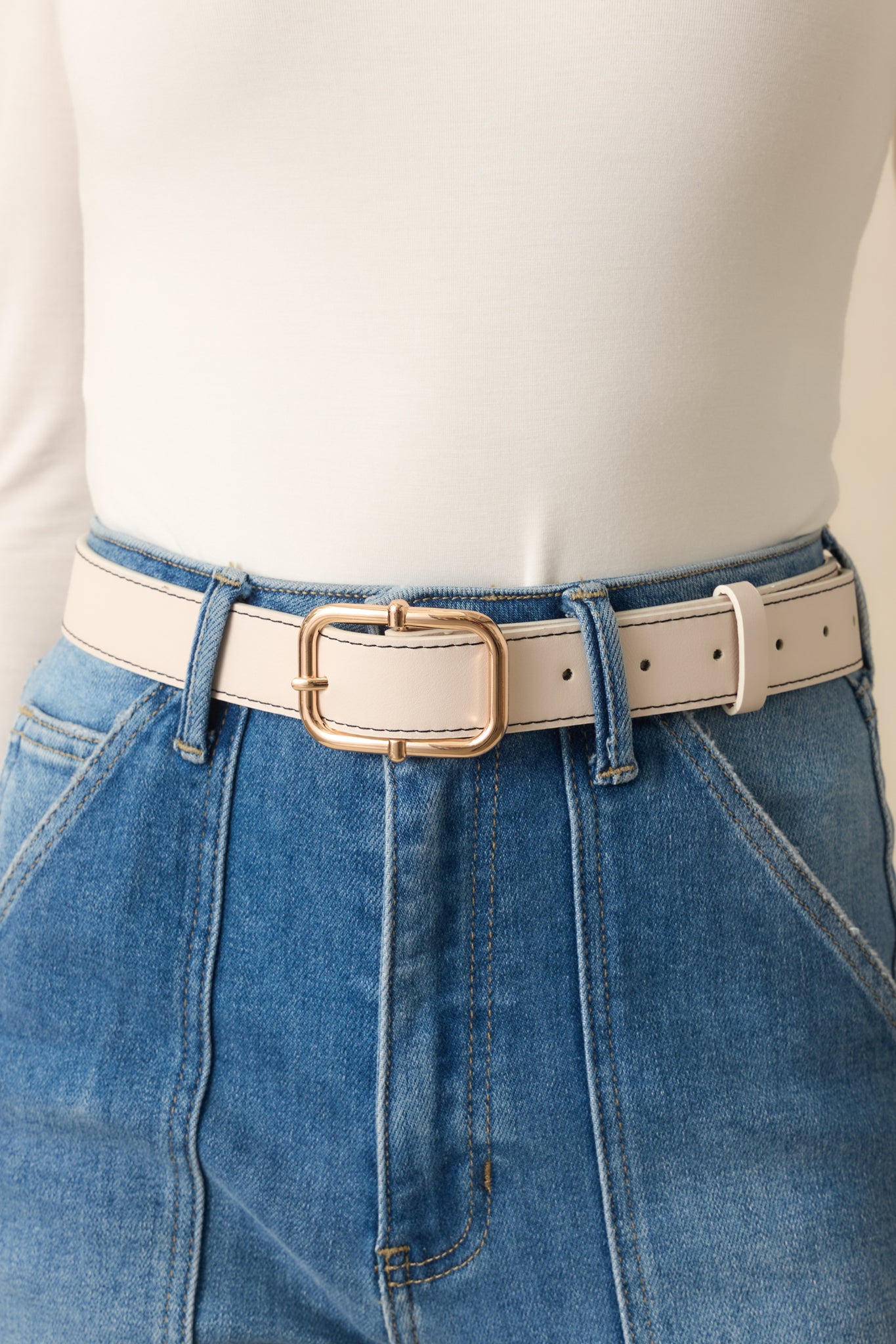 Close-up of the belt showing the gold square buckle, stitched edges, and faux leather material.