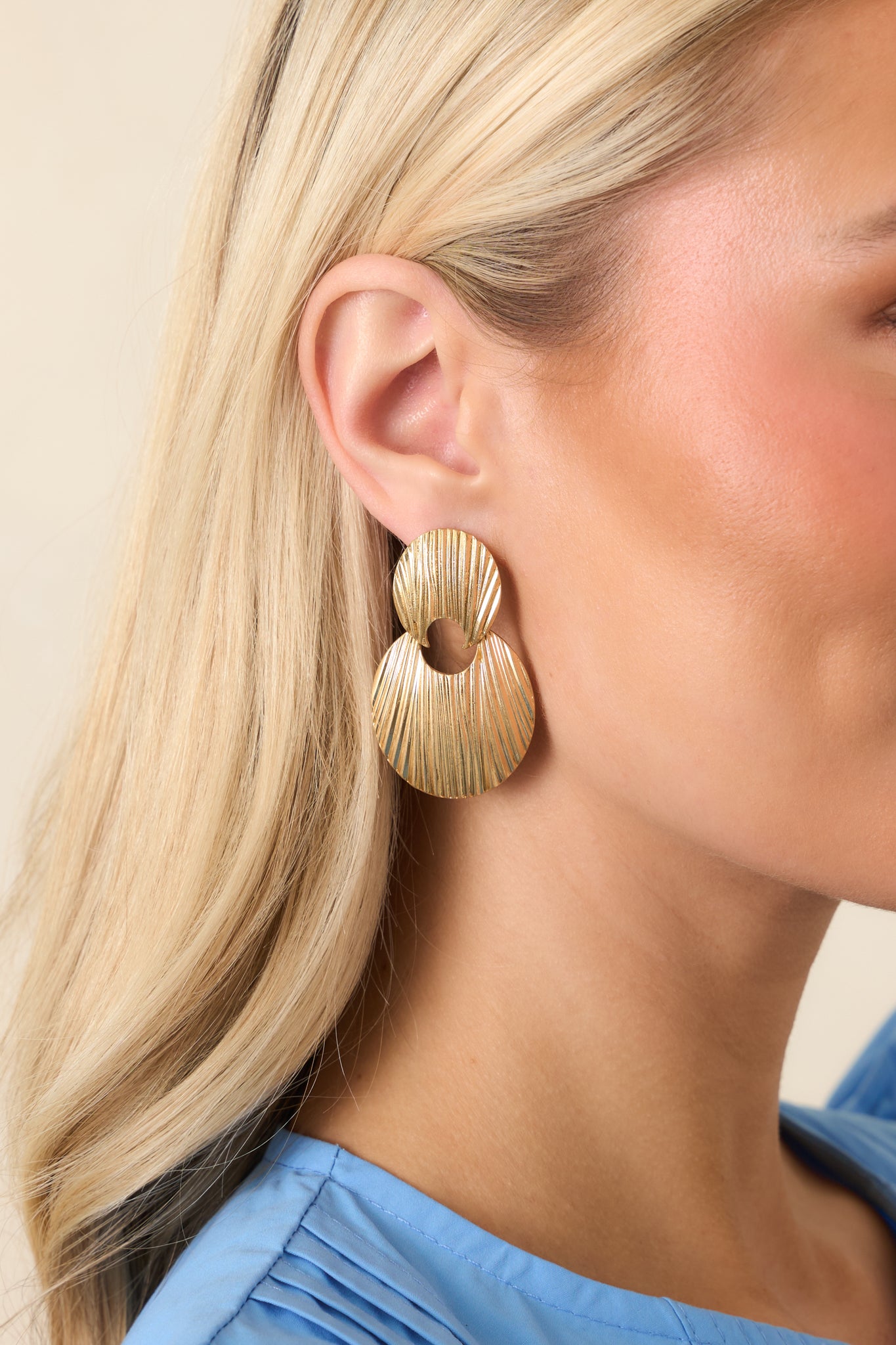 Cropped view of gold statement drop earrings with layered oval discs and ridged texture.