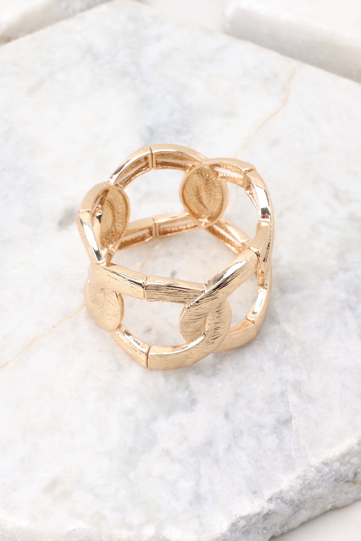 Angled view of the gold stretch bracelet on a white backdrop, highlighting the dimensional shine of each link.