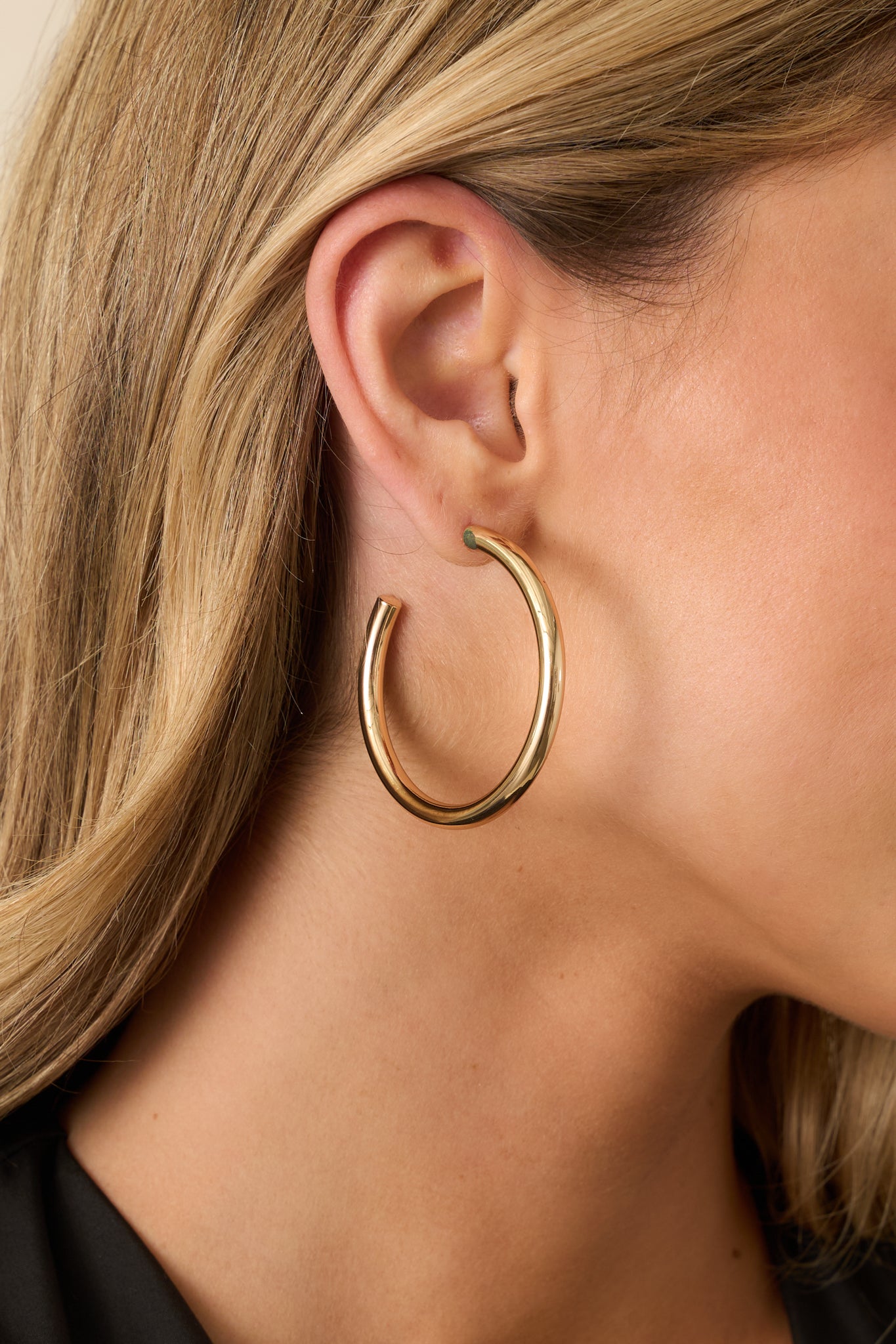 Detailed close-up showing the smooth gold surface, thickened hoop shape, and secure post backing.