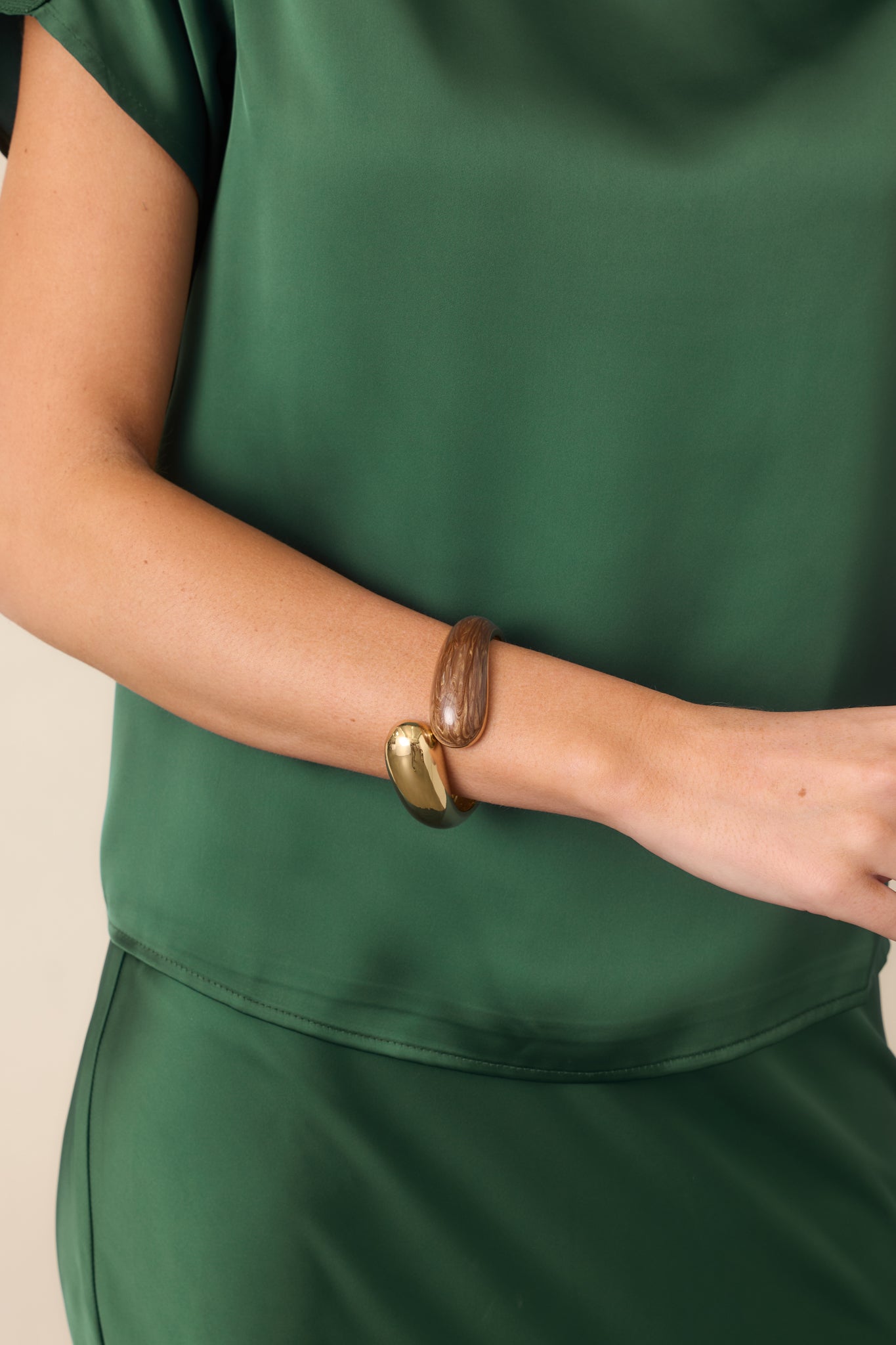 Open cuff bracelet featuring a polished gold-tone end paired with a rounded brown marbled end.