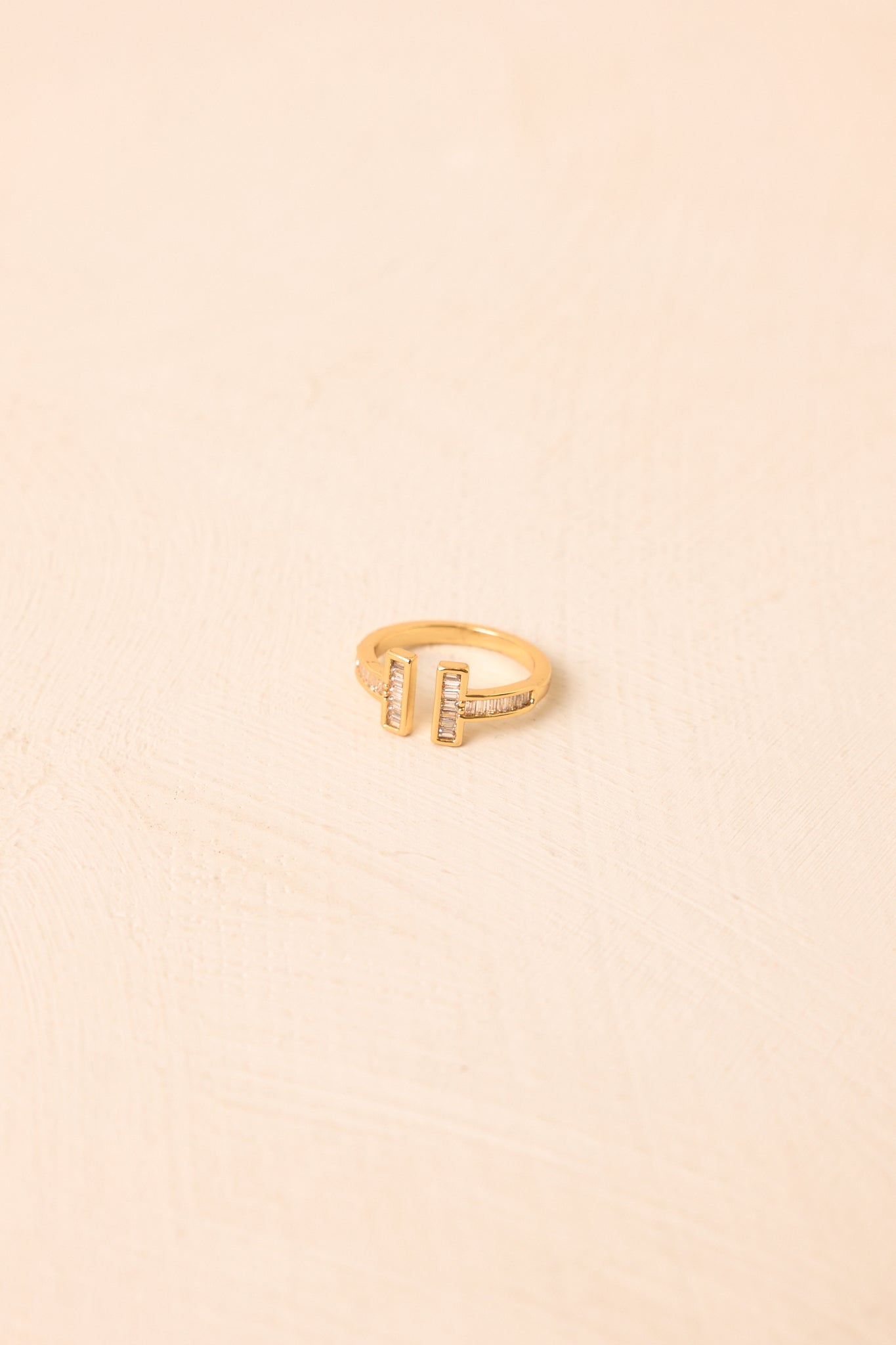 Sleek gold-tone ring showcasing an open bypass silhouette, sparkling crystal accents, and a modern geometric design.