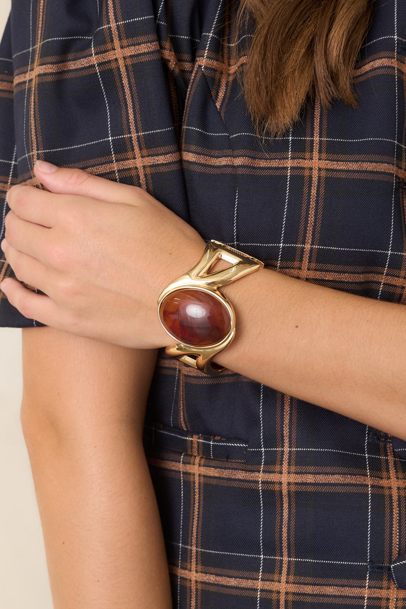 Sculptural gold-tone cuff bracelet featuring an oval amber-tone cabochon framed by sleek geometric detailing.