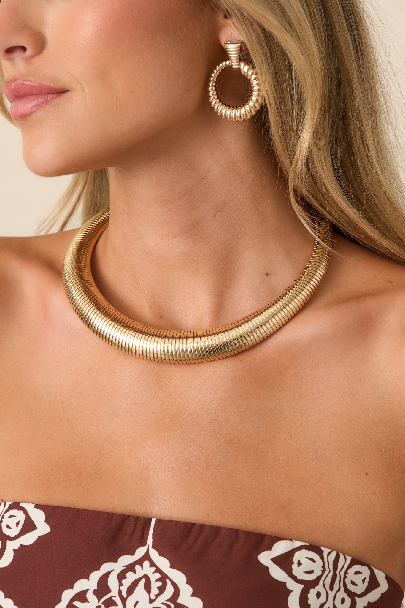Gold-tone statement necklace featuring a wide curved silhouette, fine ribbed detailing, and a sculptural graduated design that creates a bold neckline accent.