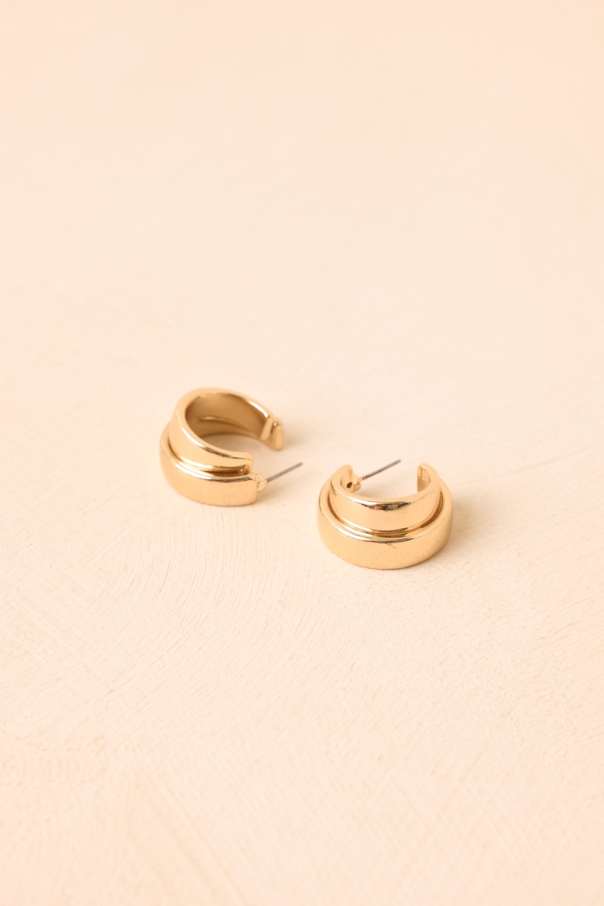 Polished gold-tone earrings featuring a chunky curved silhouette and sculptural detailing with a smooth, rounded finish.